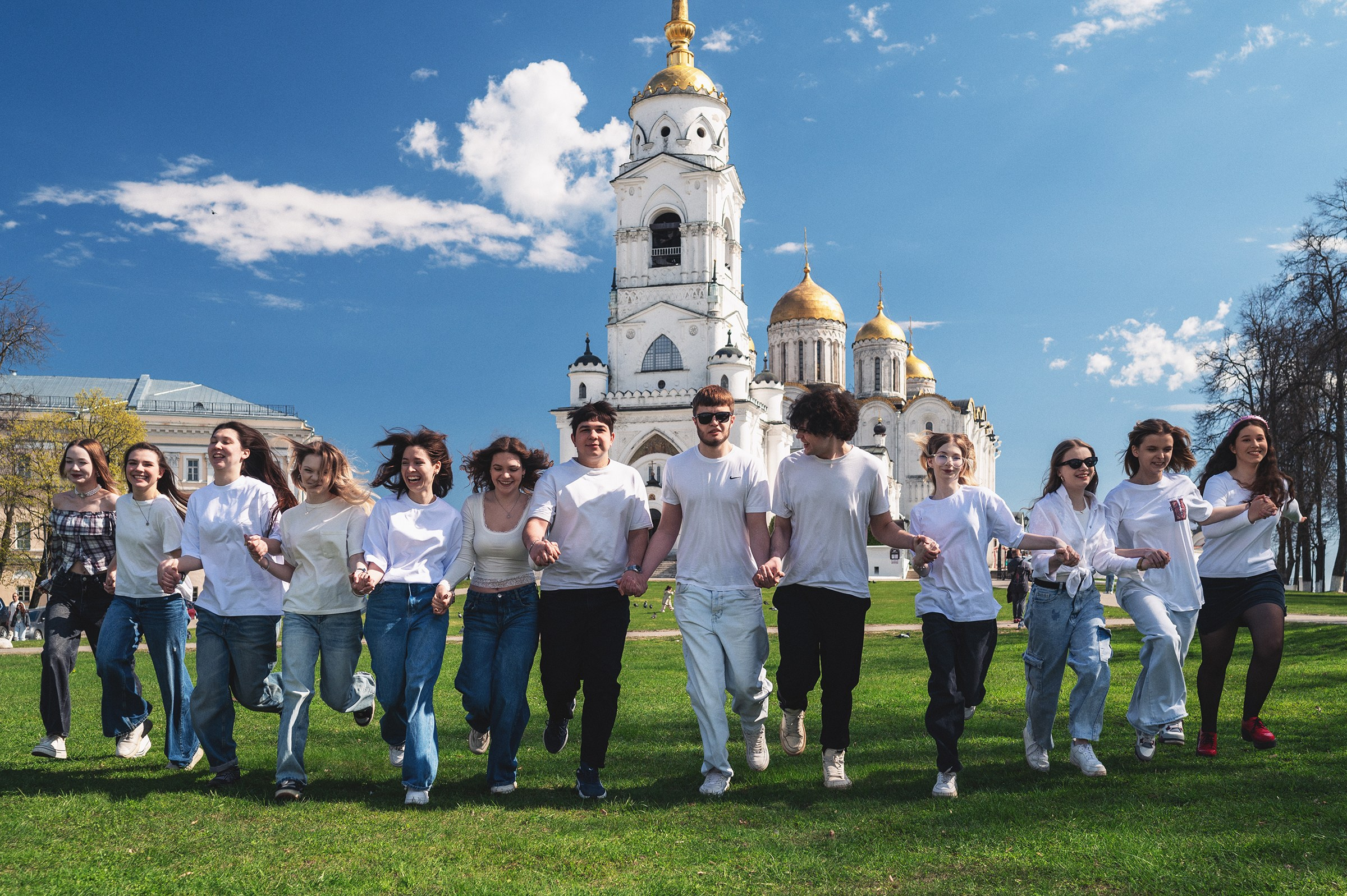 Услуга фотосессия для пары. Молодая пара муж с женой позируют на лавочке на фоне Успенского собора во Владимире.