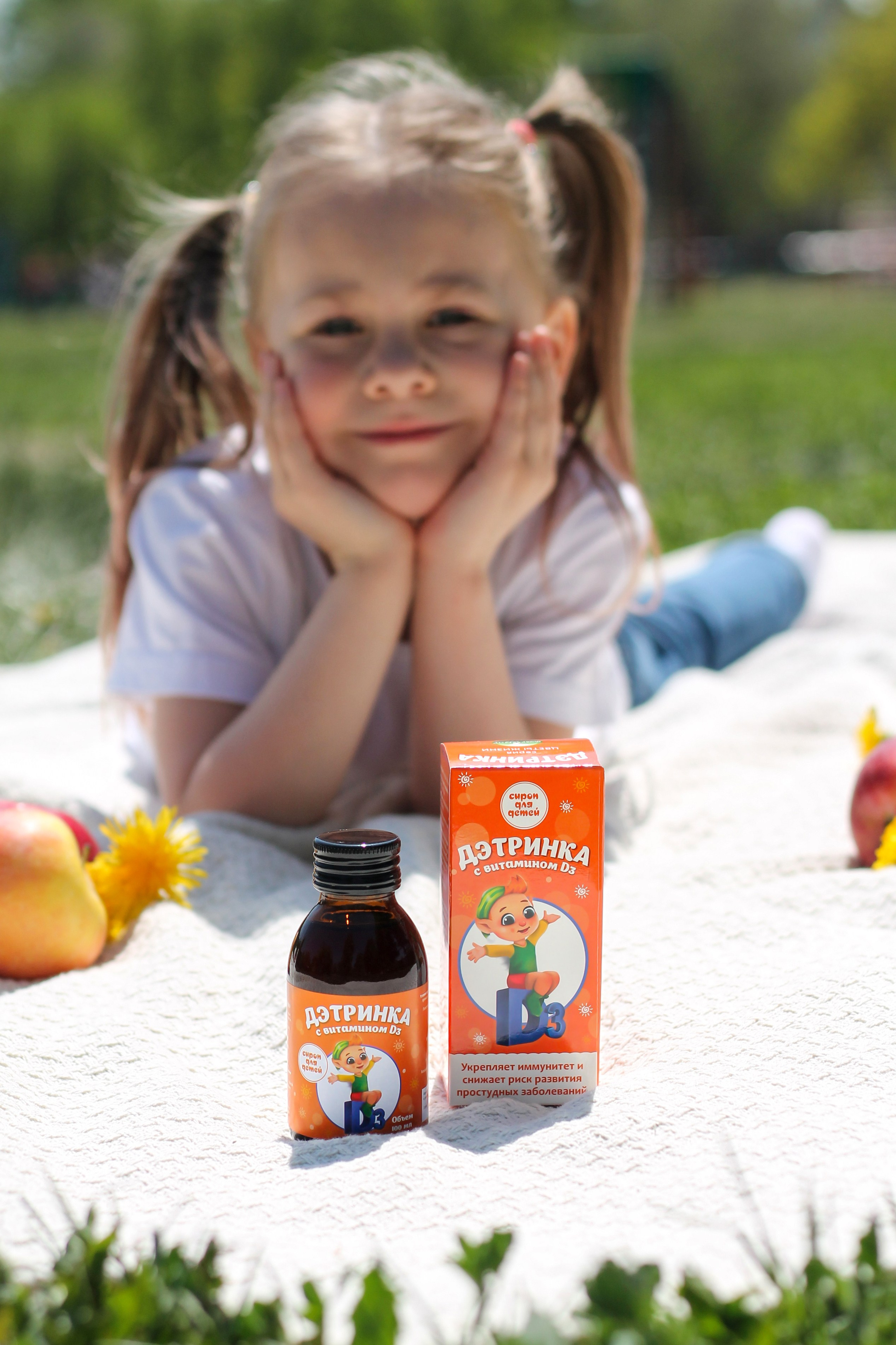 маленькая девочка лежит на пледе летом, рядом стоит флакончик с сиропом. Фотограф для маркетплейсов в Барнауле
