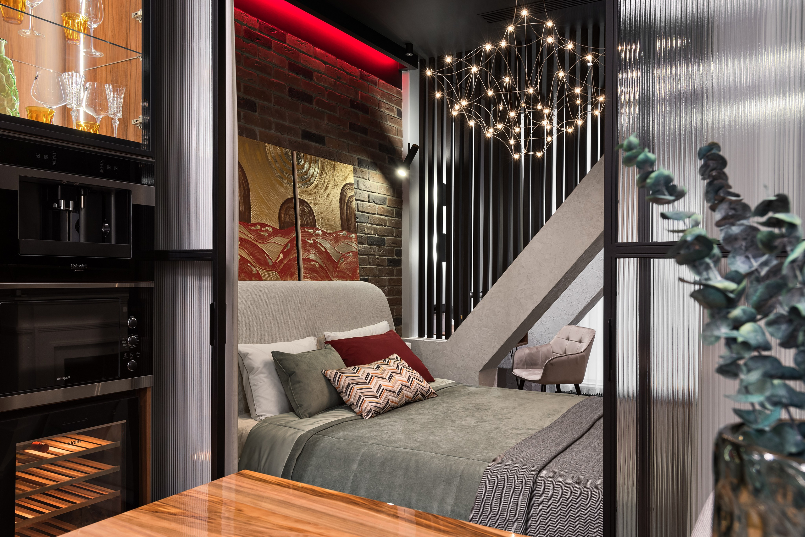 Спальня в стиле лофт: кирпичная стена, красная подсветка, стеклянные перегородки и дизайнерская люстра.