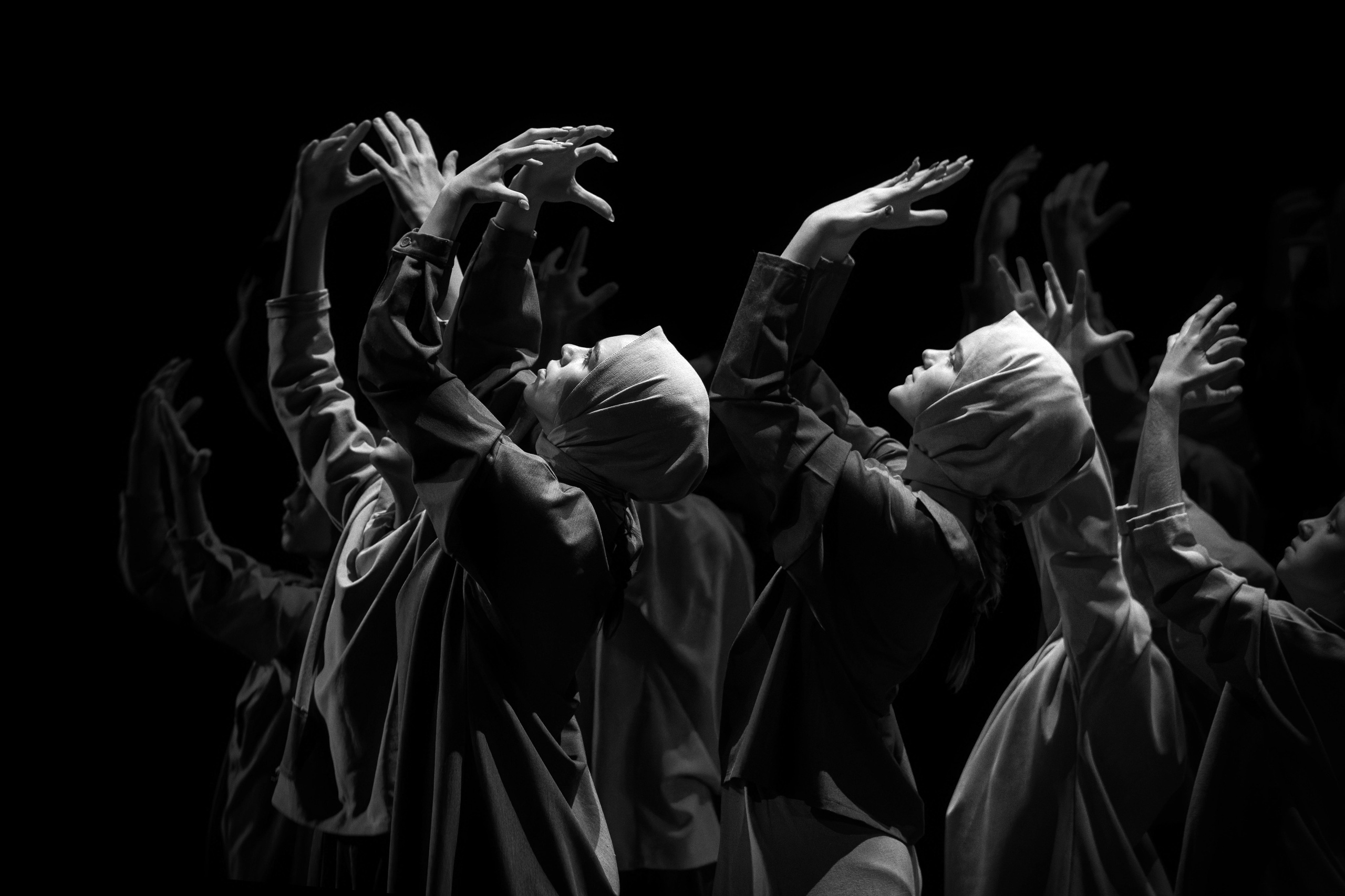 Танцоры в капюшонах с поднятыми к небу руками, молитвенный танец, духовная хореография, черно-белое фото