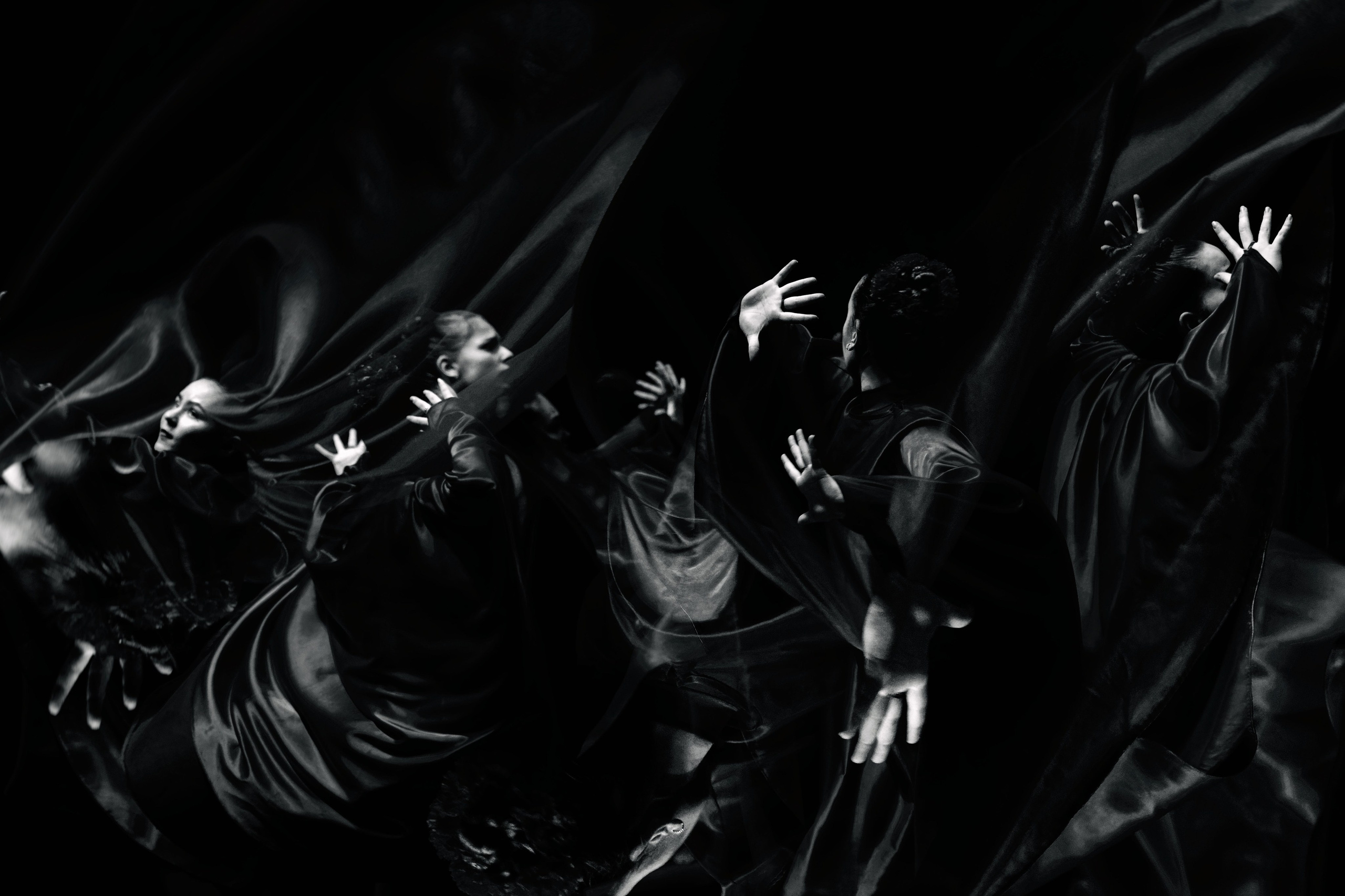 Черно-белое фото танцоров в темных flowing одеждах с поднятыми руками, драматичное освещение, реквием, современный танец
