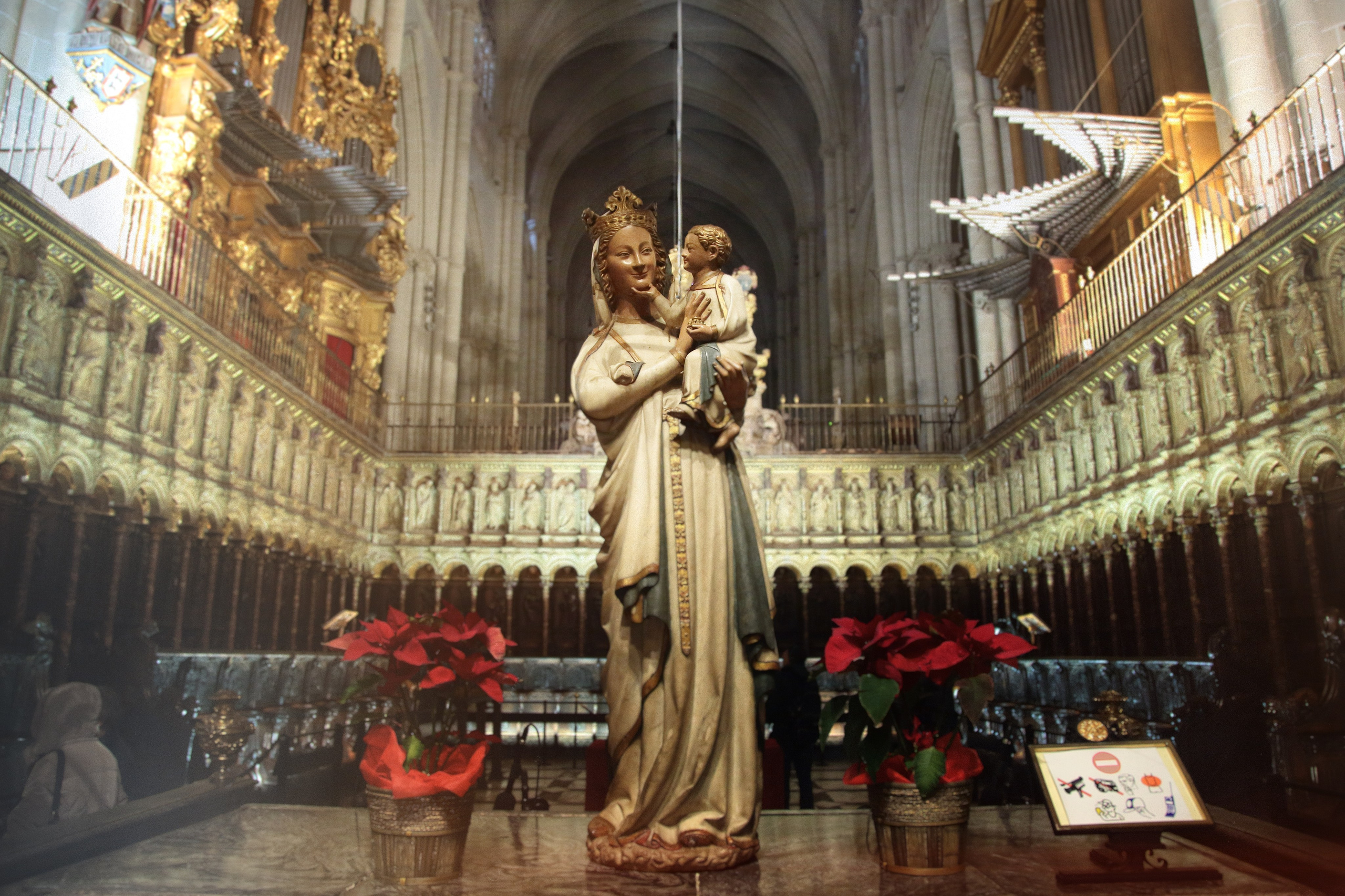 Статуя Мадонны с младенцем в готическом соборе, золотой алтарь и красные пуансеттии, интерьер церкви
