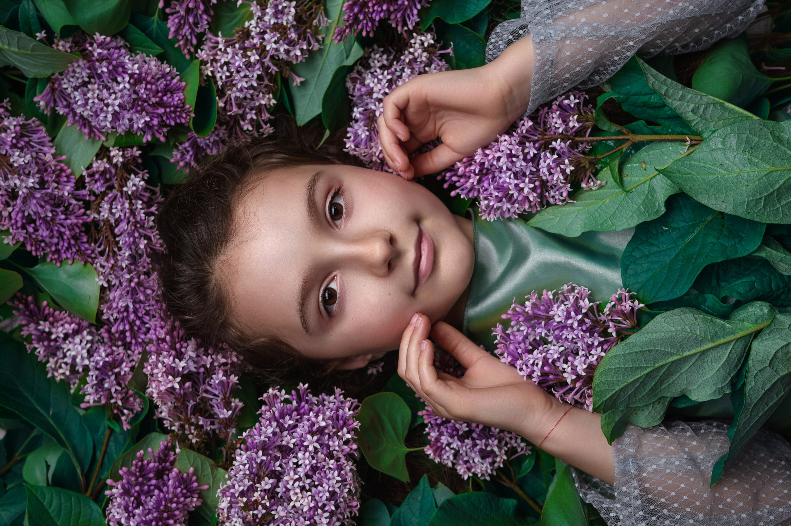 Детские фотосессии Владивосток - портрет девочки лежа сверху в цветах сирени