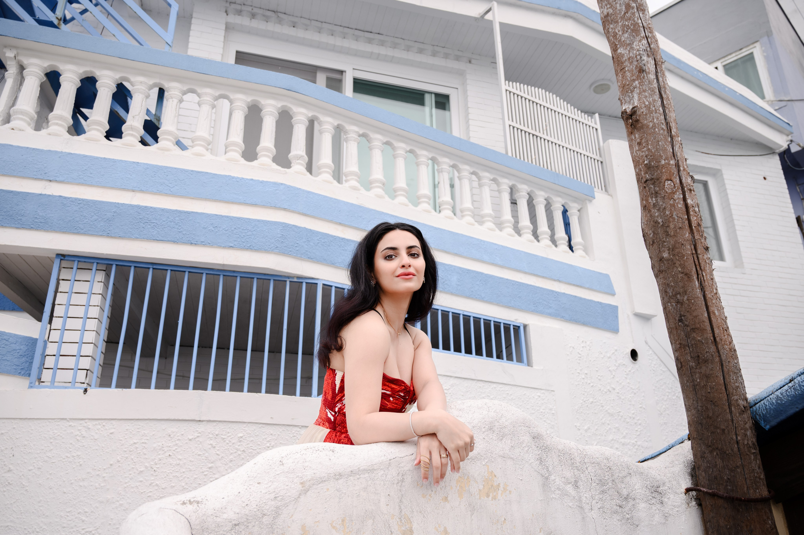 Woman in a red dress on the terrace of a white house in Huinnyeoul Culture Village, Busan — travel photoshoot · 부산 여행 스냅