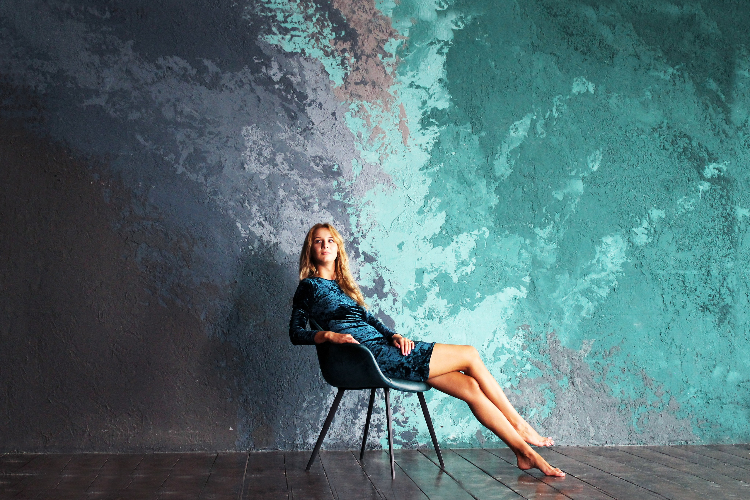 Девушка в платье,сидит на стуле,на фоне цветной стены