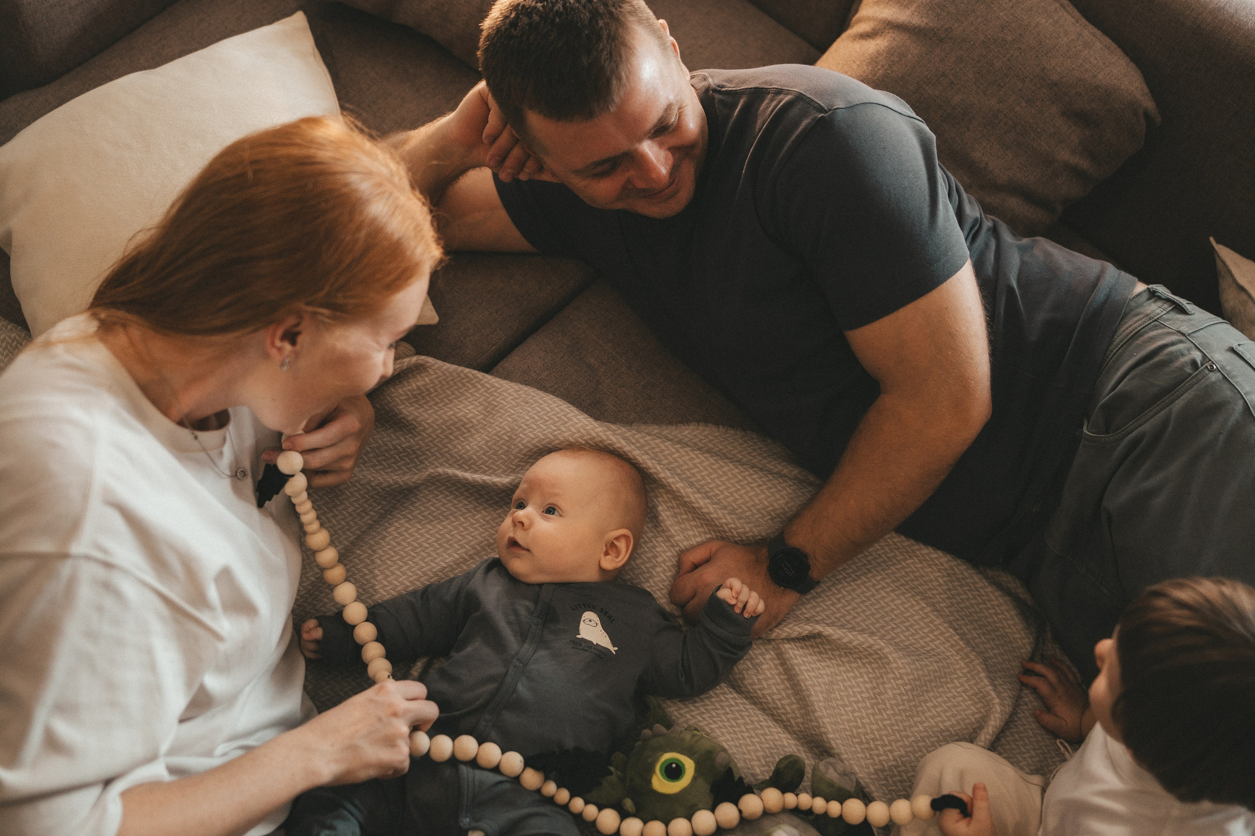 маленькая девочка держит за руки папу и маму на берегу моря