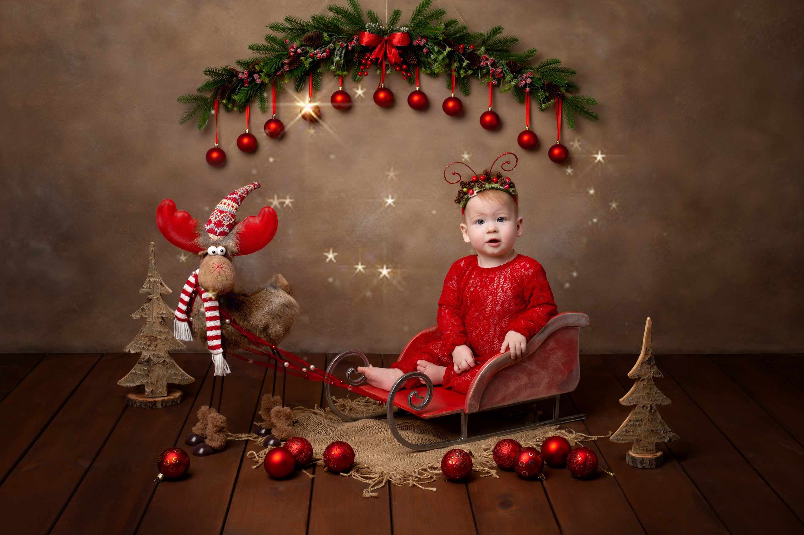 На олене в деревянных санях среди красных шаров.