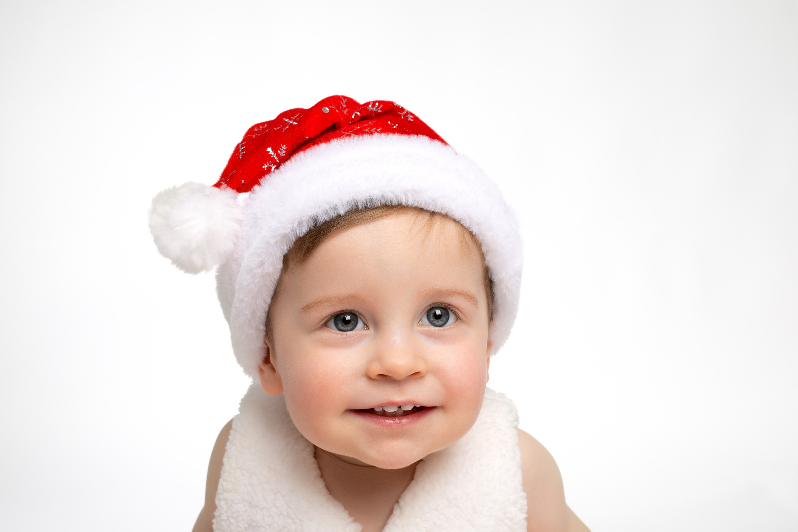Крупный портрет ребёнка в новогодней шапке с бомбошкой.