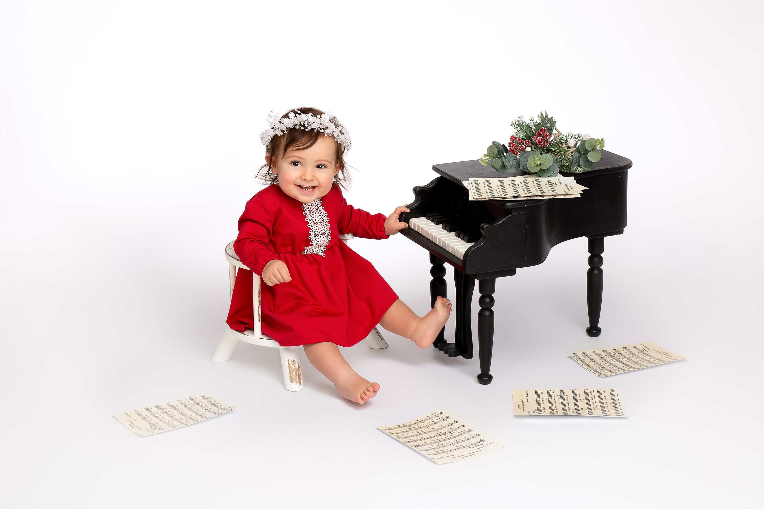 Ребёнок в красном платье сидит за чёрным роялем.