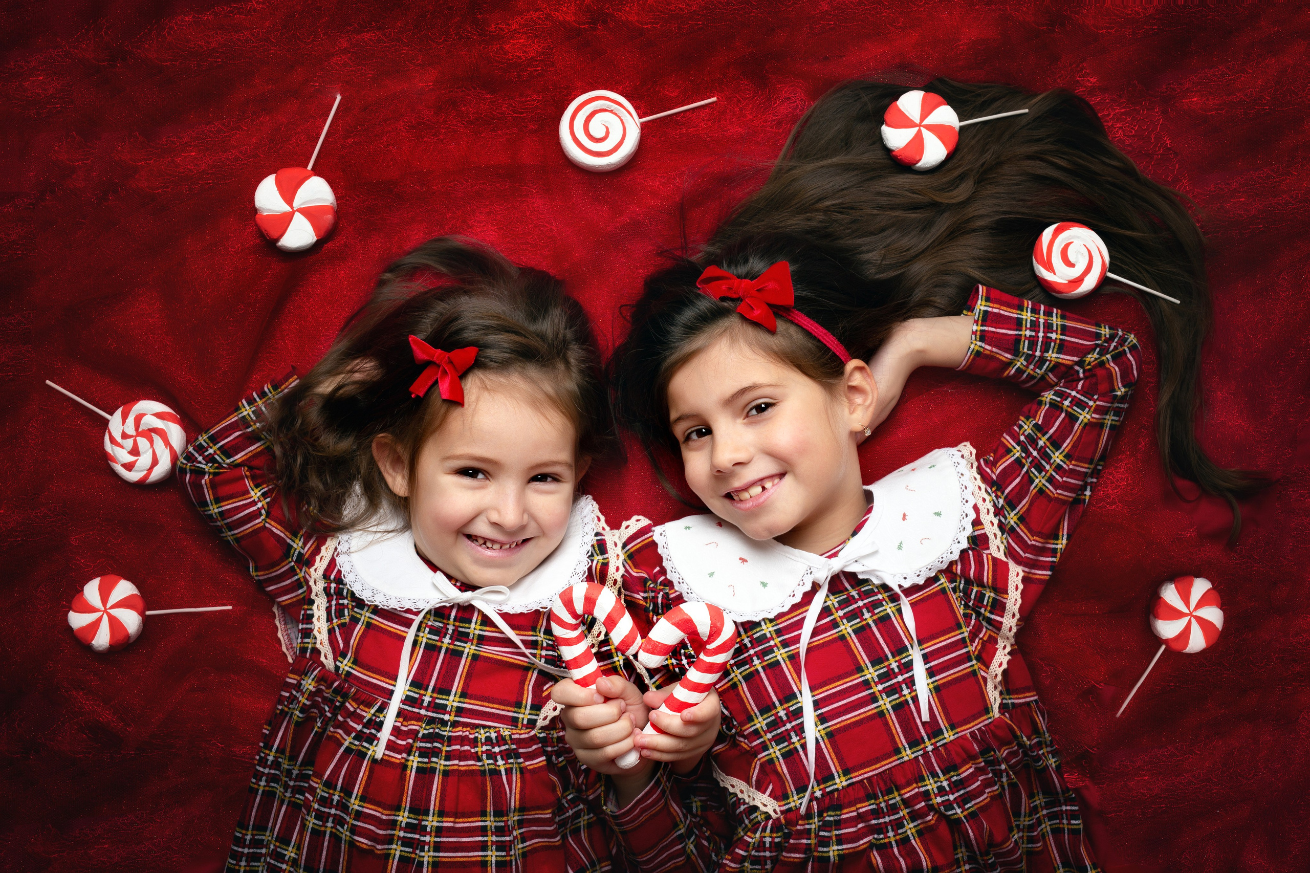 Детский крупный новогодний портрет через леденцы на красном фоне.