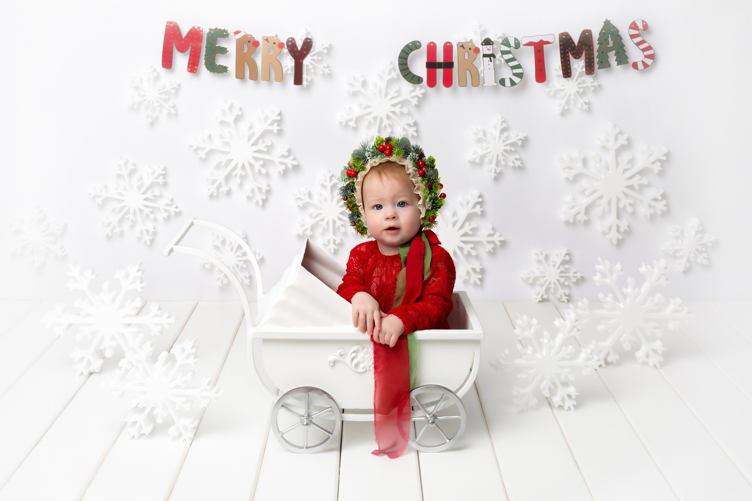 Ребёнок в цветочной шапке в маленькой белой коляске.