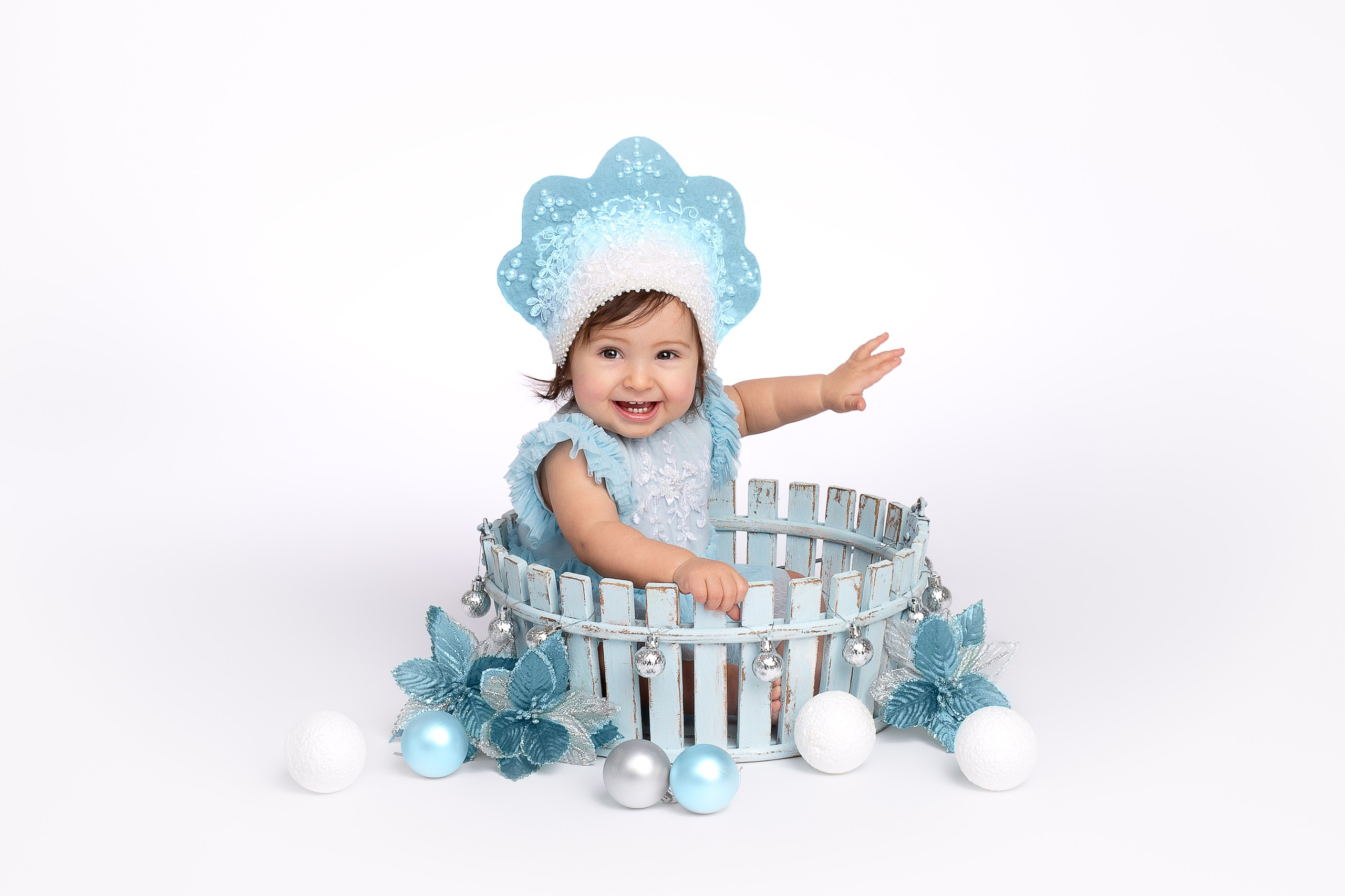 Маленькая девочка в голубом платье и короне снегурочки.