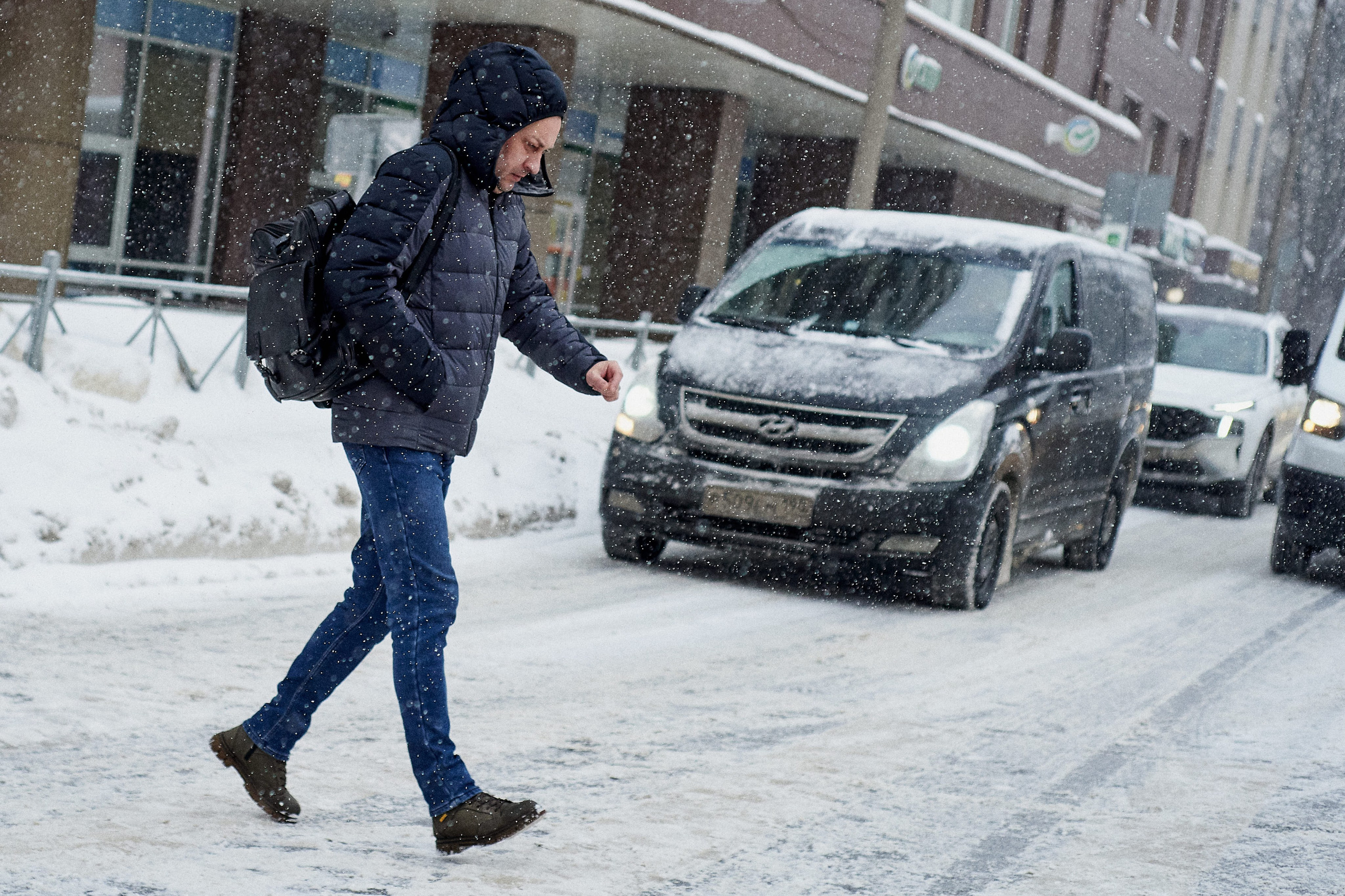 Heavy snowfall in Russia. Pedestrian crossing the street during a snowstorm in a Russian city. Winter urban scene.