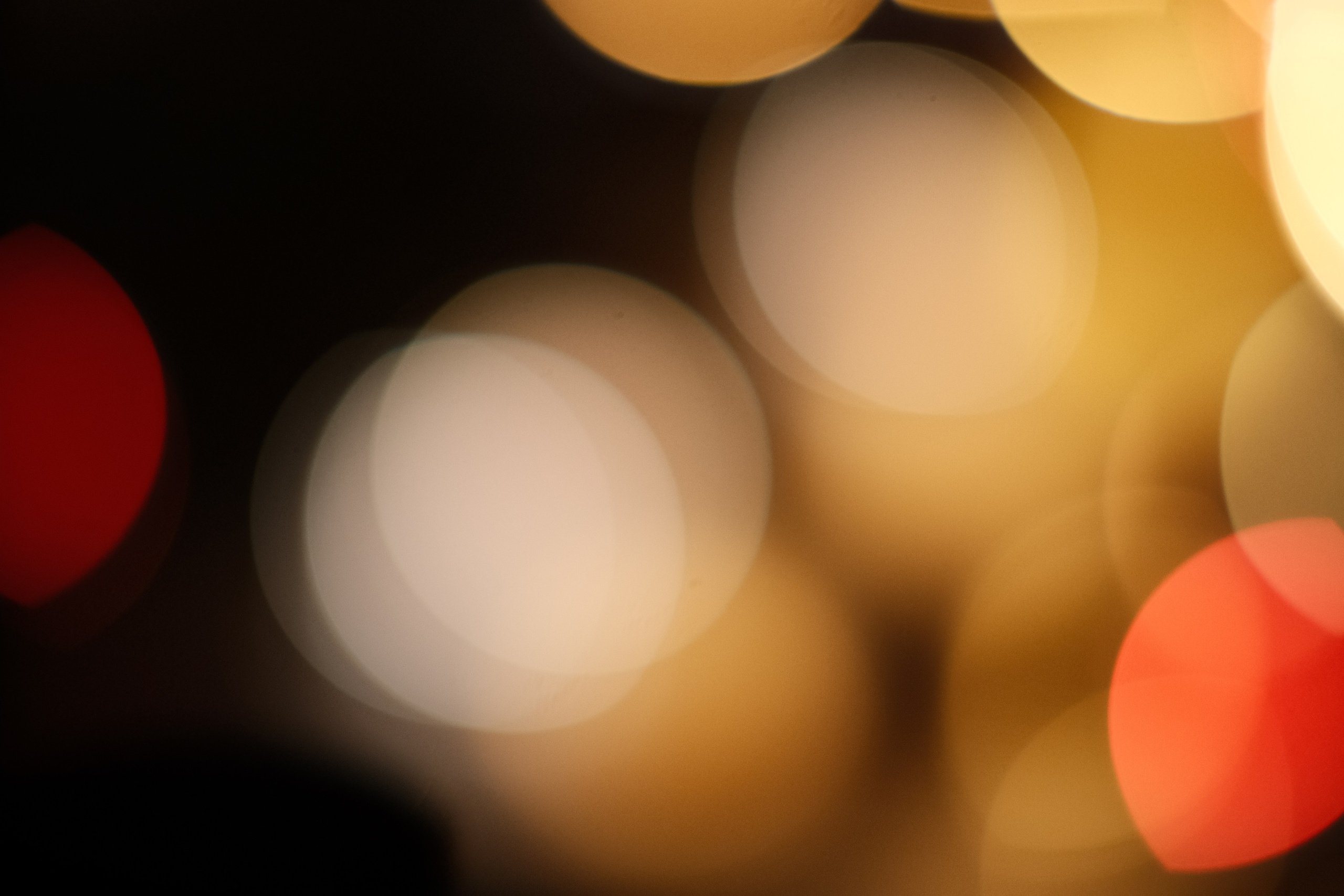 Абстрактная фотография: размытые круги боке в теплых тонах — золотые, белые, красные огни на темном фоне, художественное размытие