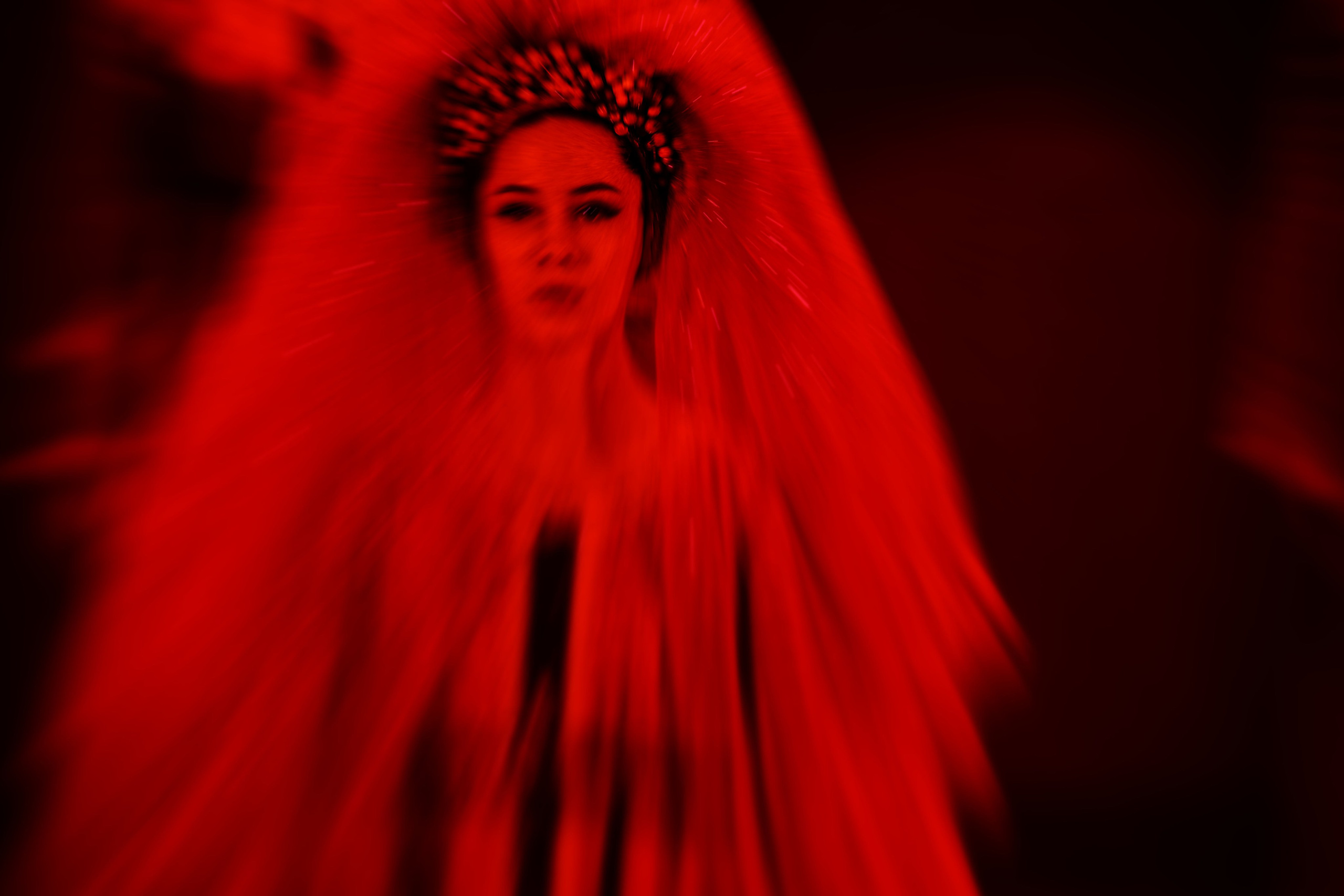 Женщина с декоративным головным убором в красном свете с эффектом радиального размытия, мистический образ, художественный портрет