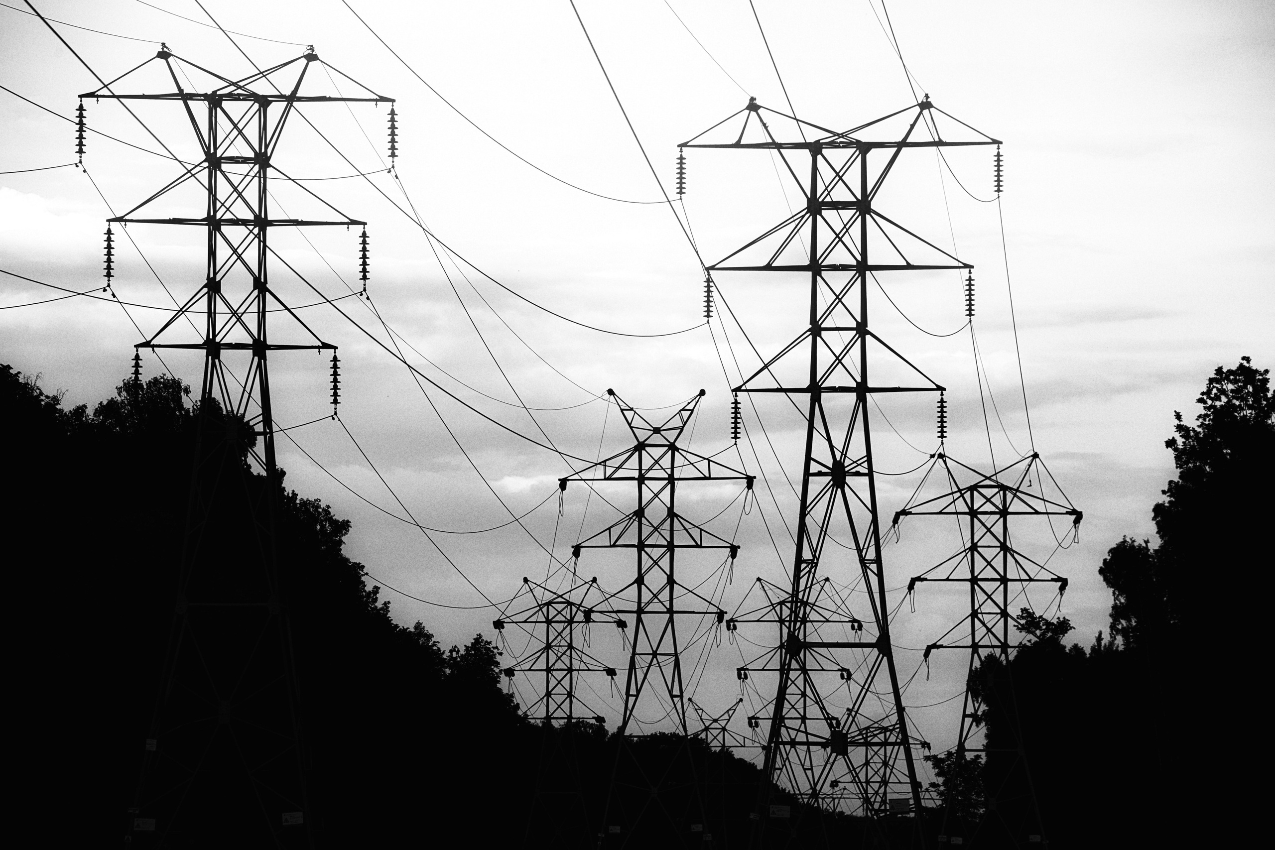 Множество высоковольтных опор ЛЭП создающих геометрический узор, силуэты на фоне неба, индустриальный пейзаж