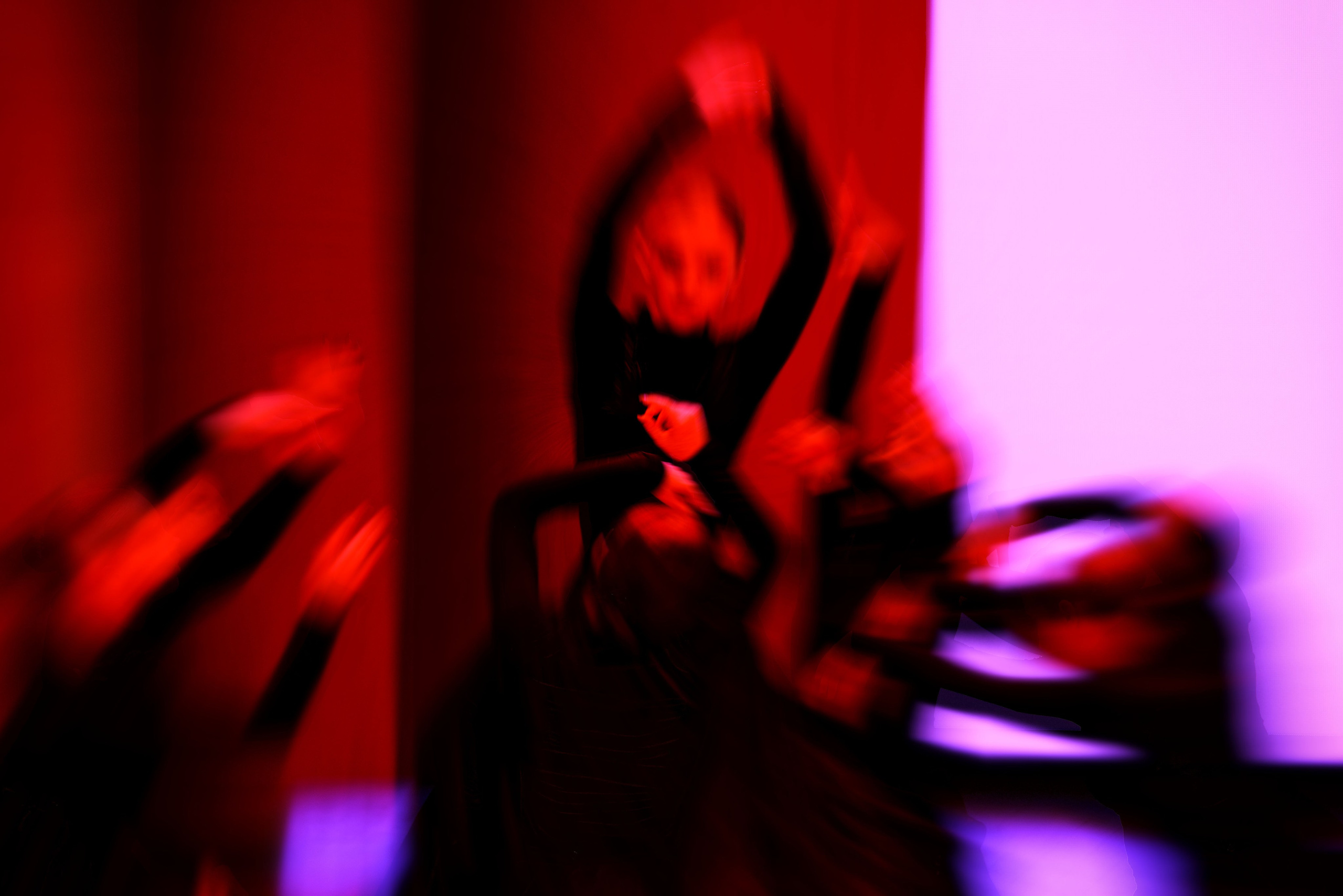 Группа танцоров в красно-фиолетовом освещении с эффектом размытия движения, множественные силуэты, динамичная композиция