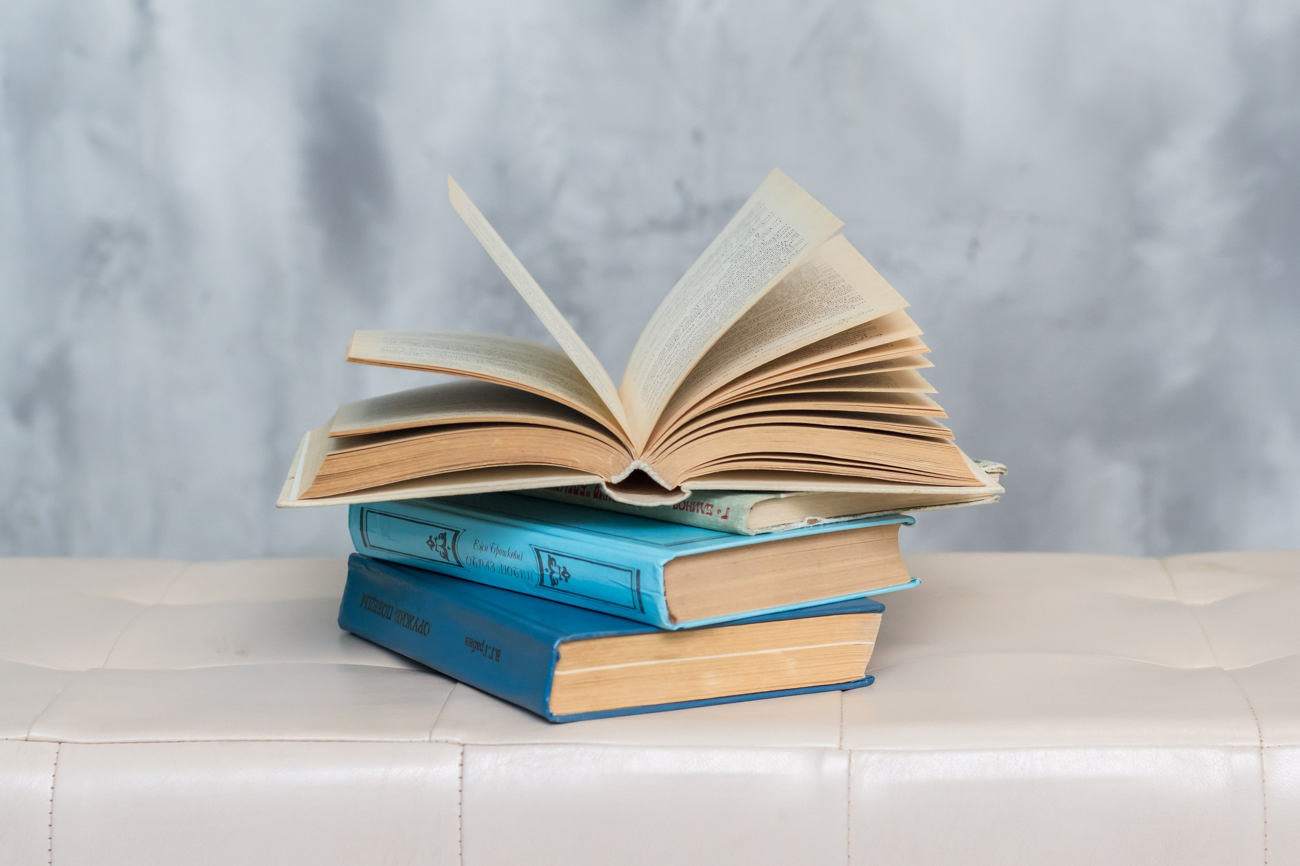 Три книги расположенные стопкой, верхняя книга открыта