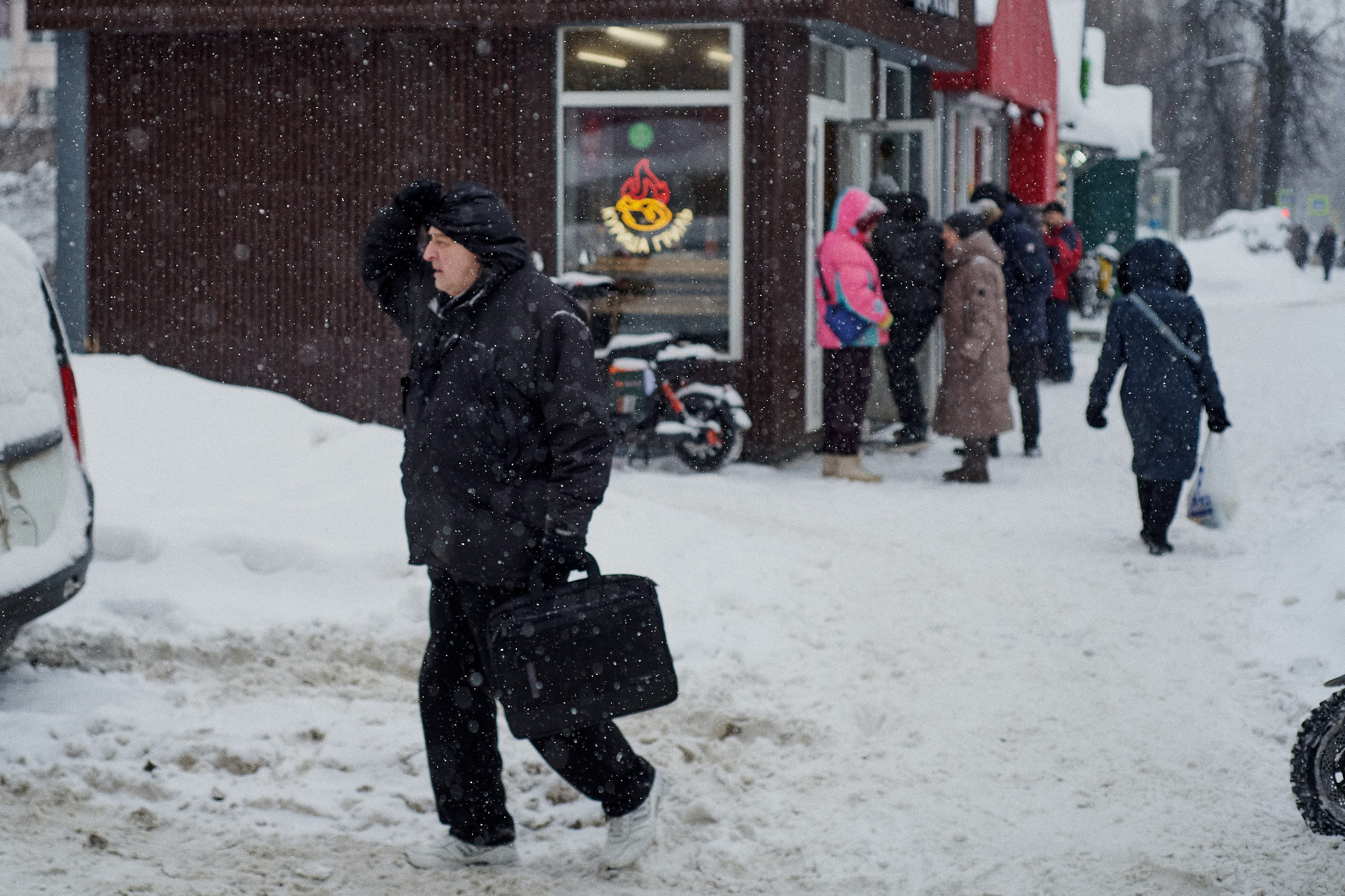 Residents on a snow-covered street. People walking along a street heavily covered with snow during snowfall in Russia.