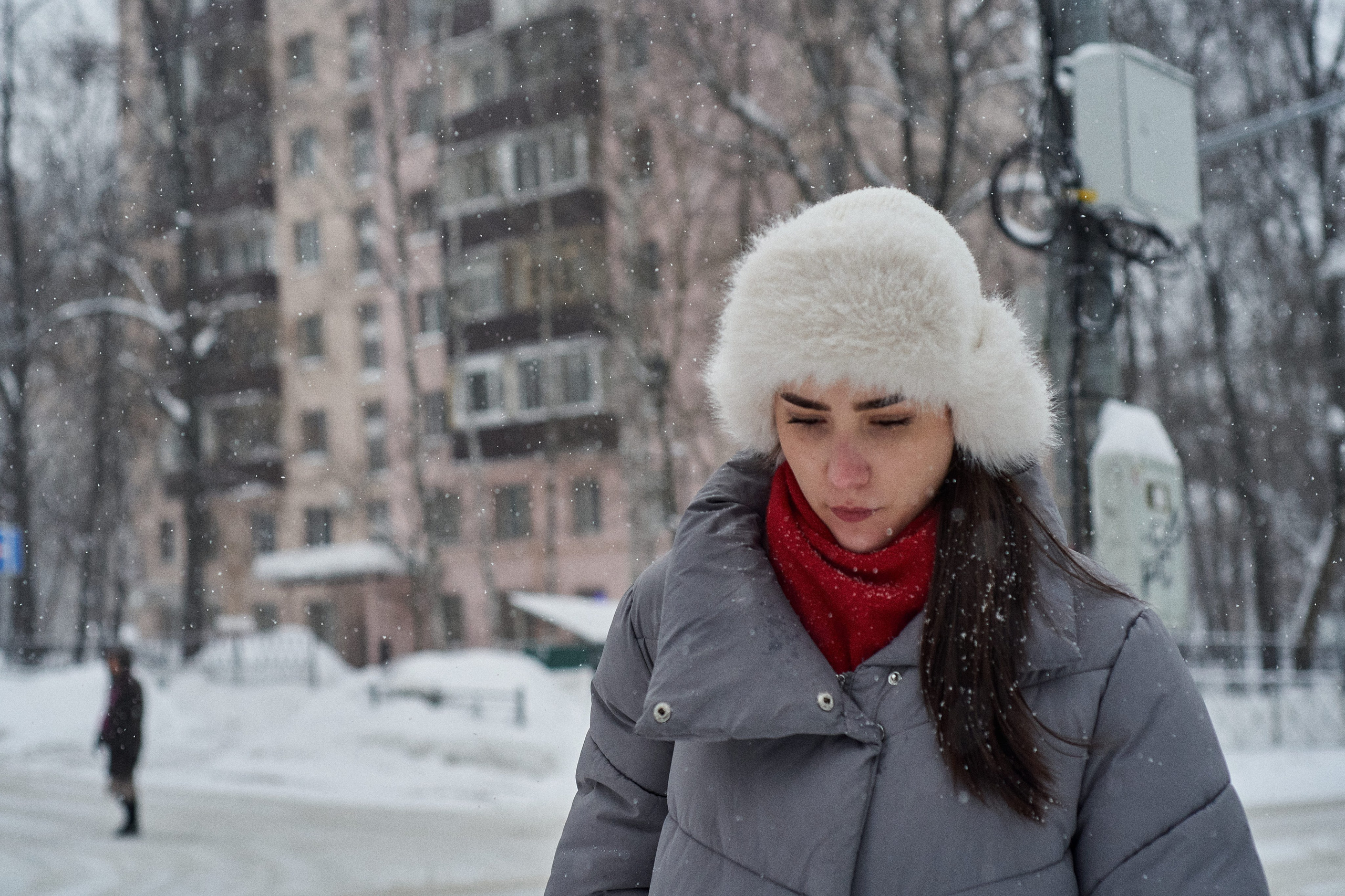 Woman in a fur hat during snowfall. Russian woman in a traditional fur hat standing outdoors during a winter snowstorm.