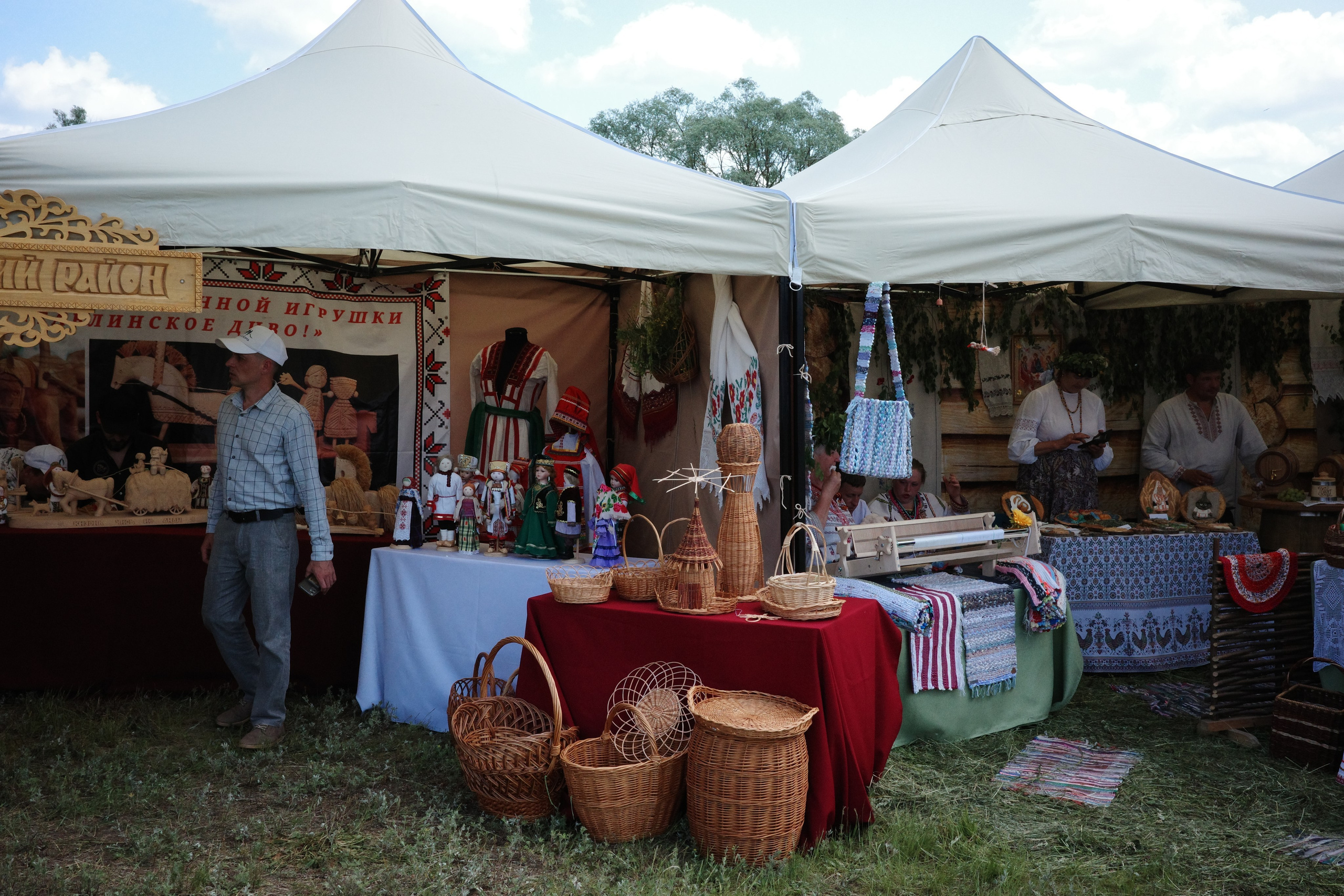 Богатый сувенирный стенд с деревянными игрушками, плетёными корзинами, народными куклами и расписными изделиями