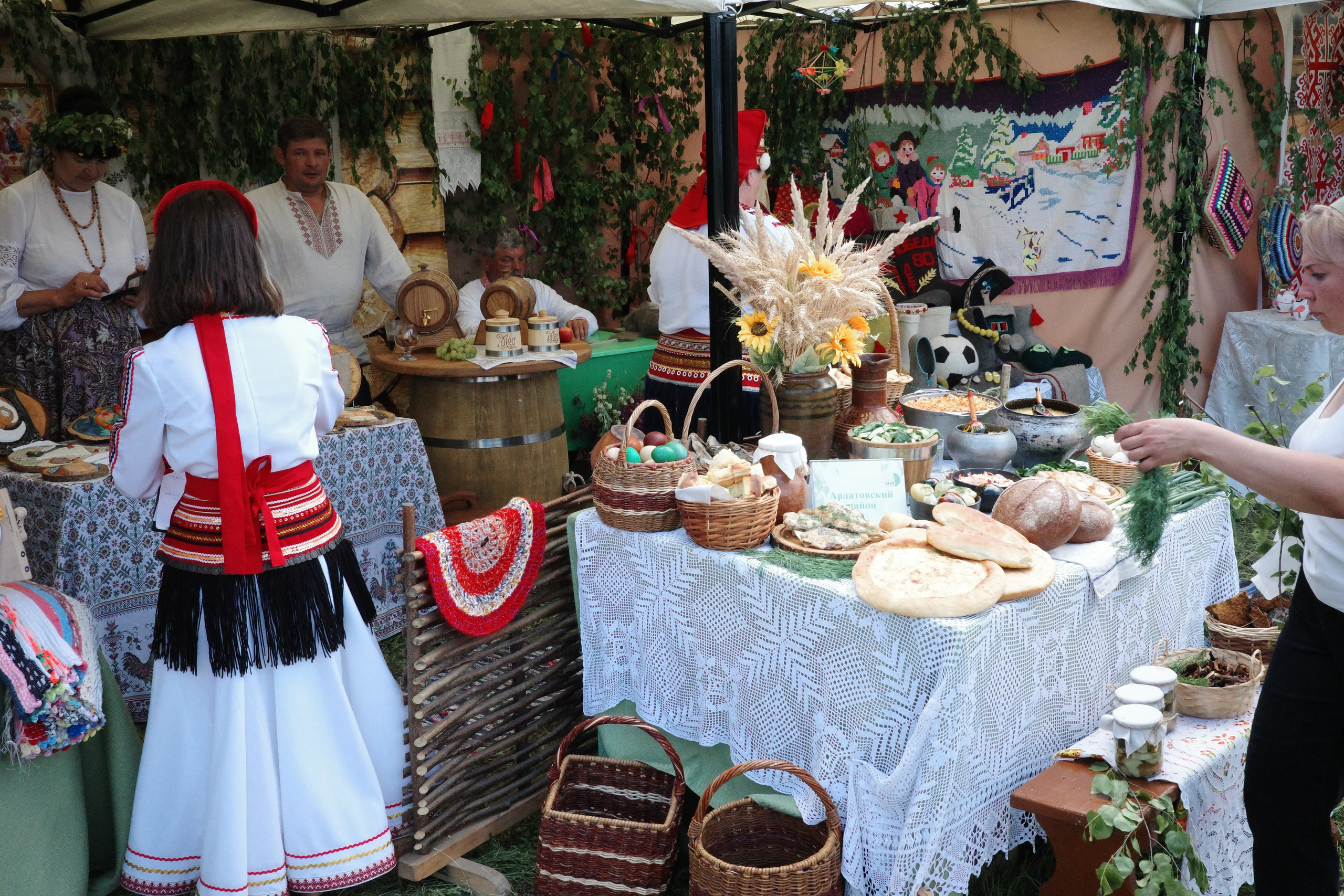 Праздничный стол с традиционными мордовскими угощениями — пирогами, хлебом, корзинами, женщина в народном костюме