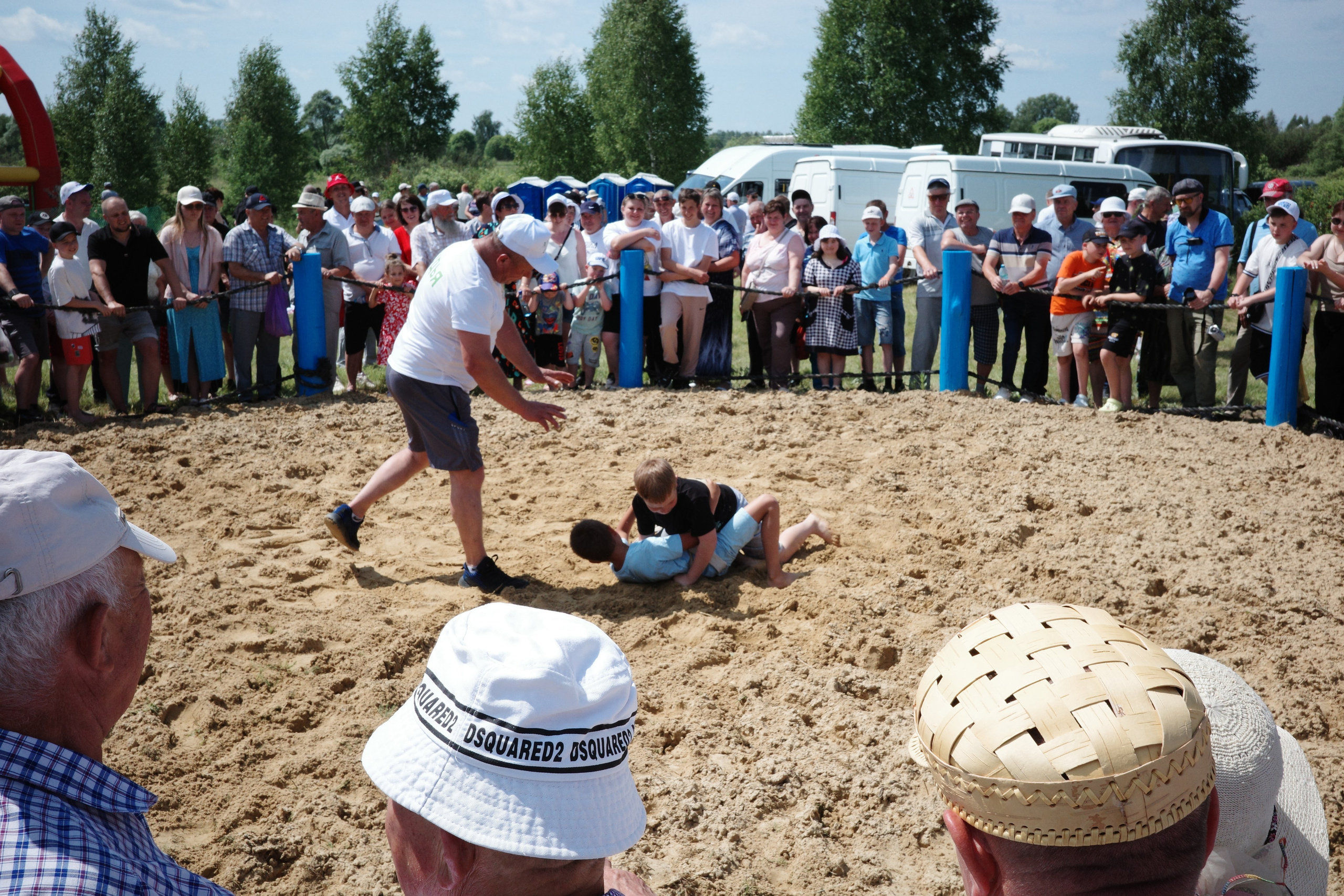 Традиционная мордовская борьба на поясах на песчаном ринге, вокруг плотная толпа зрителей в жару