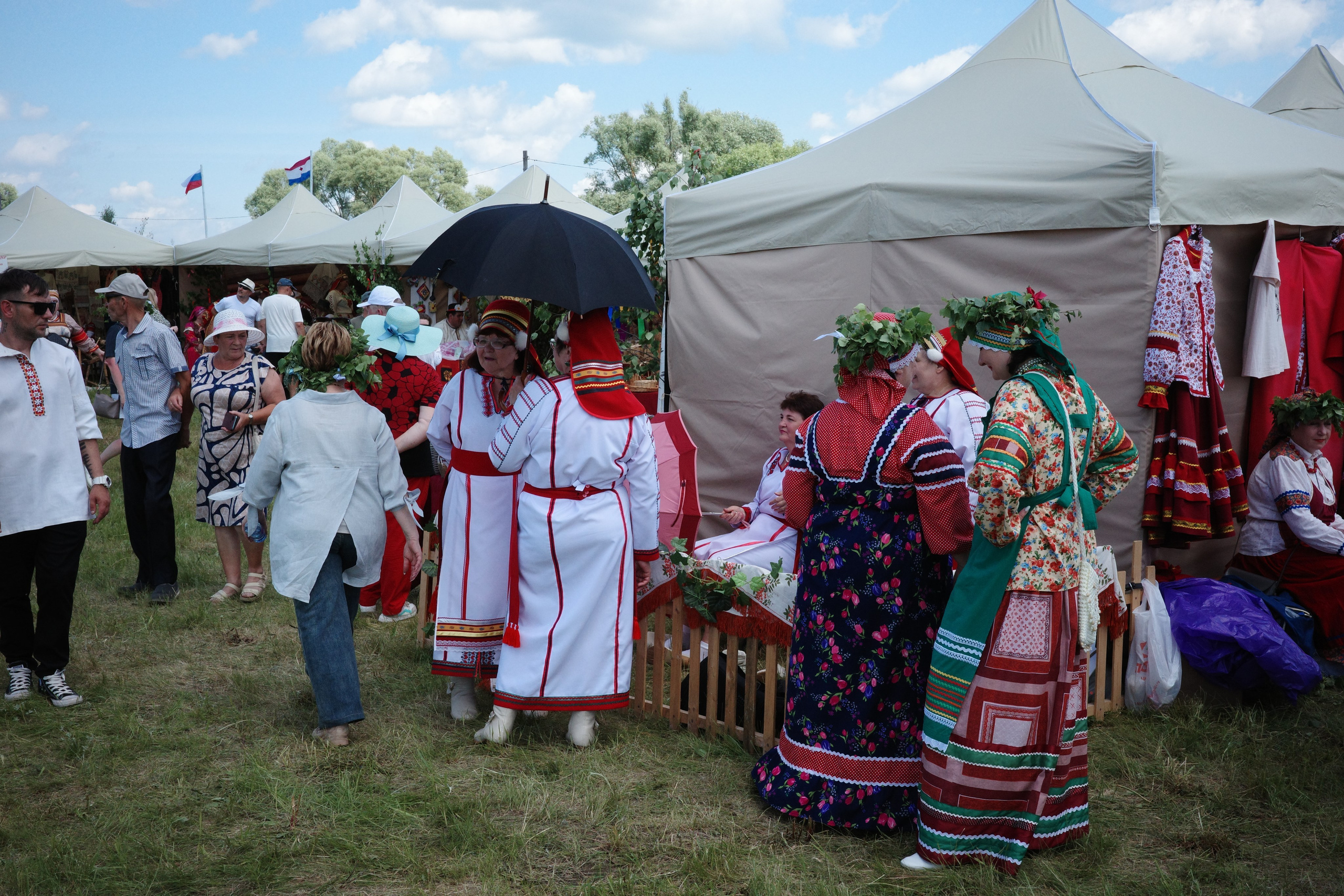 Женщины в мордовских традиционных костюмах с цветочными венками разговаривают между собой
