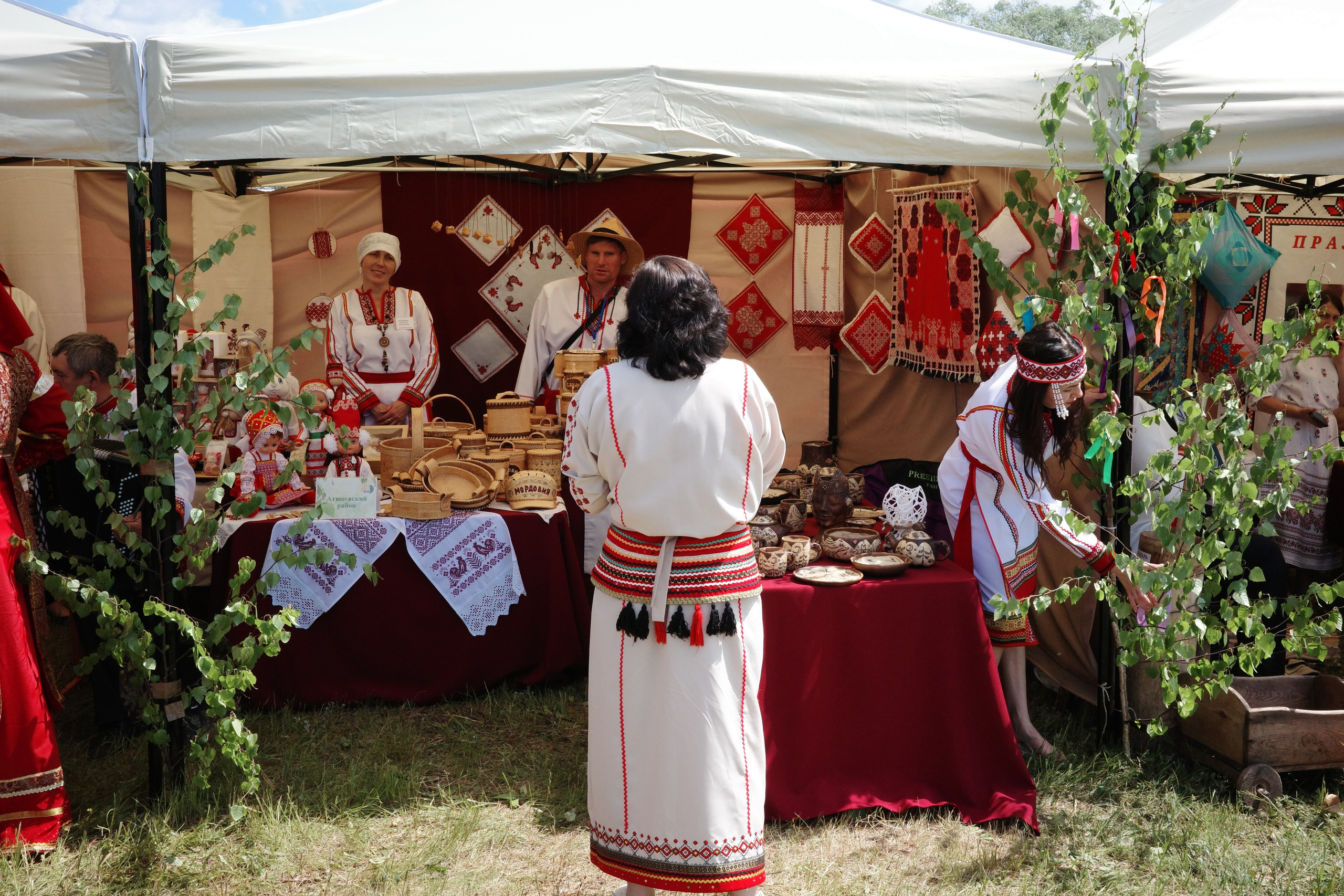 Шатёр, украшенный берёзовыми ветками, участники в белых и красных традиционных костюмах