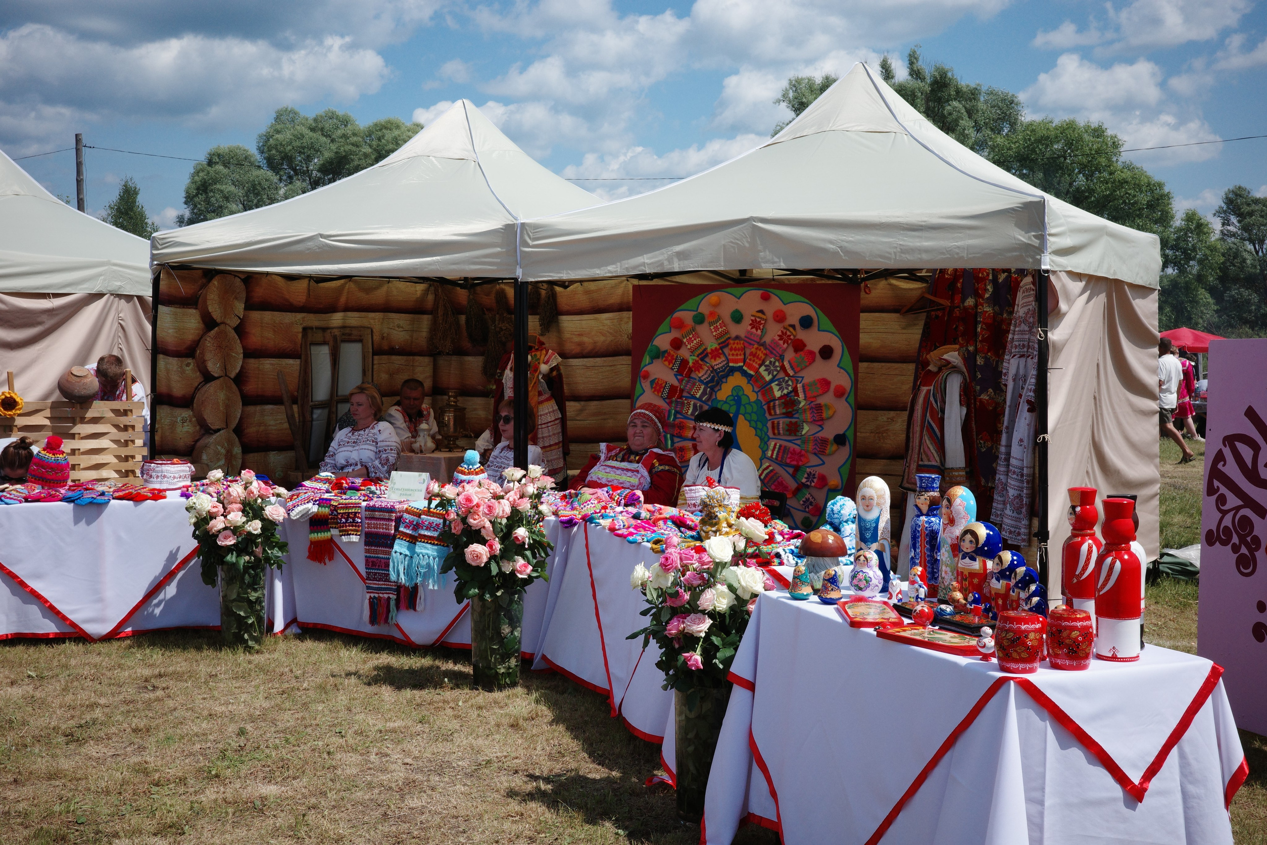 Нарядный шатёр с красными и белыми скатертями, живыми цветами, народными сувенирами и куклами