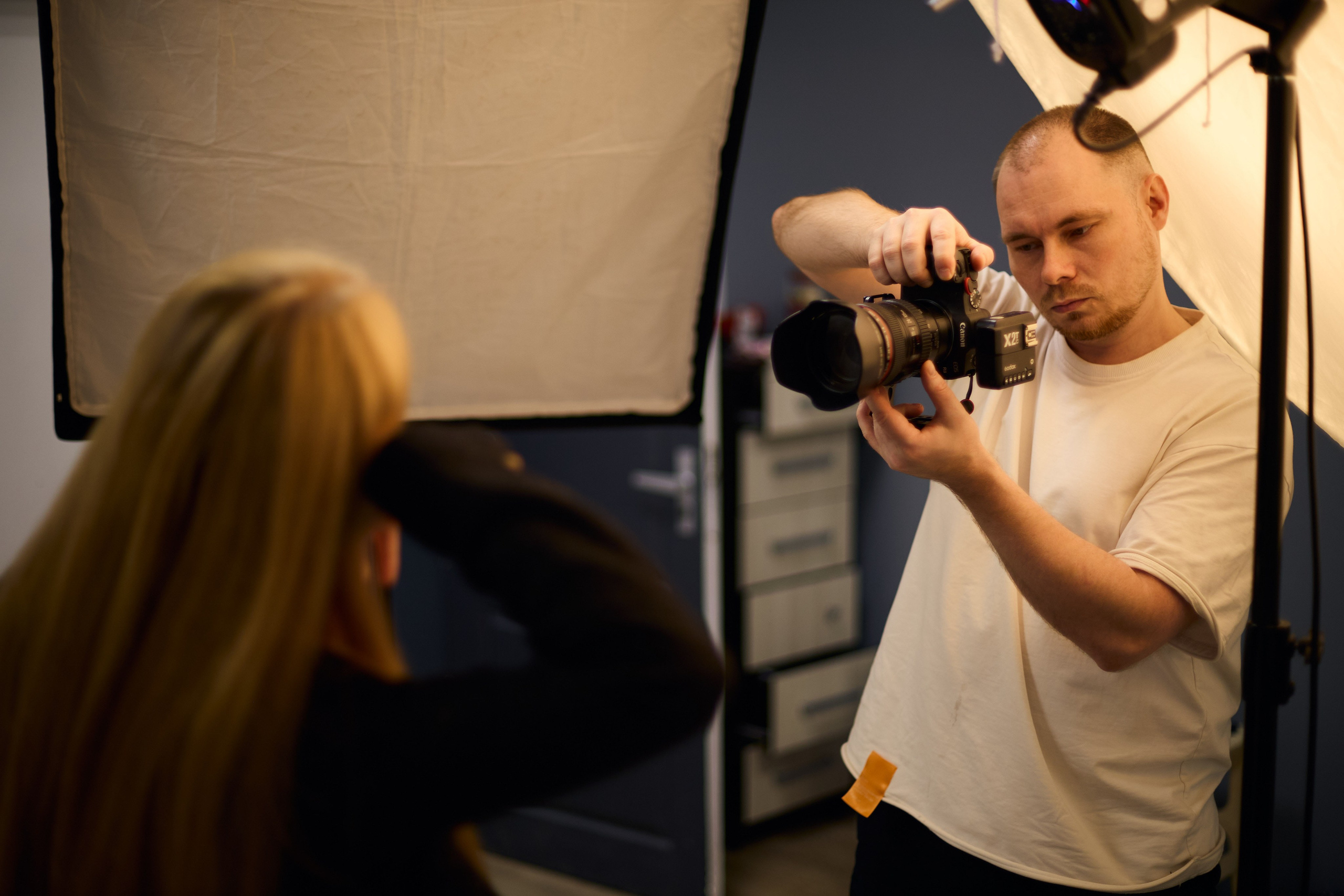 Фотограф с ассистентом за работой в студии, подготовка к предметной съёмке — иллюстрация процесса создания профессионального каталожного фото.