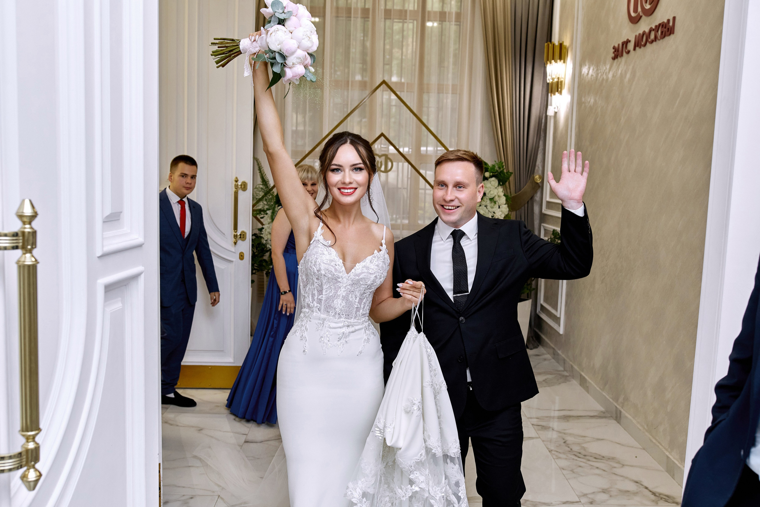 Фотограф в ЗАГС снимает молодоженов в красивом Кутузовском ЗАГСе – получилось яркое фото жениха и невесты, идущих под руку на роспись и выражающих приветствие гостям