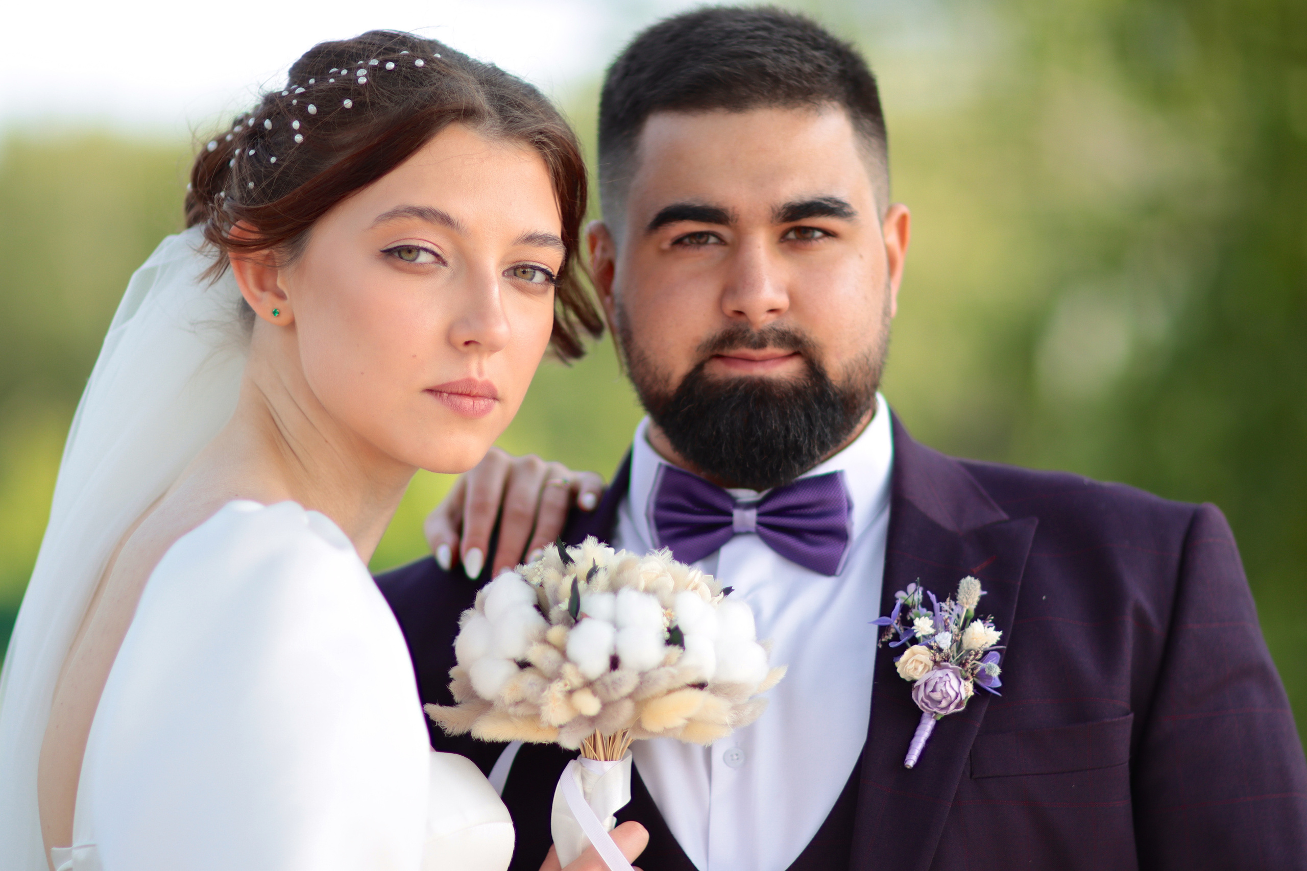 Невеста с букетом, жених в фиолетовом костюме с бабочкой.