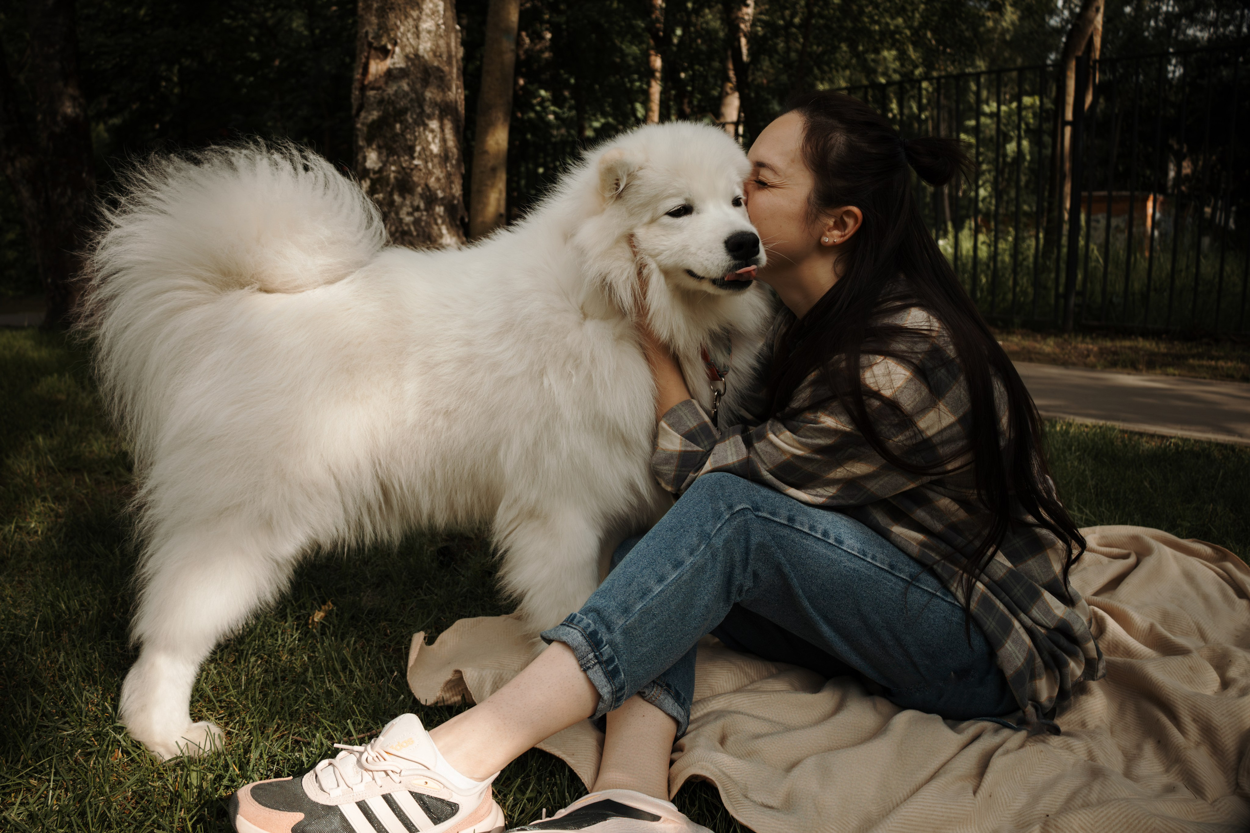 Девушка целует собаку на фотосессии в парке