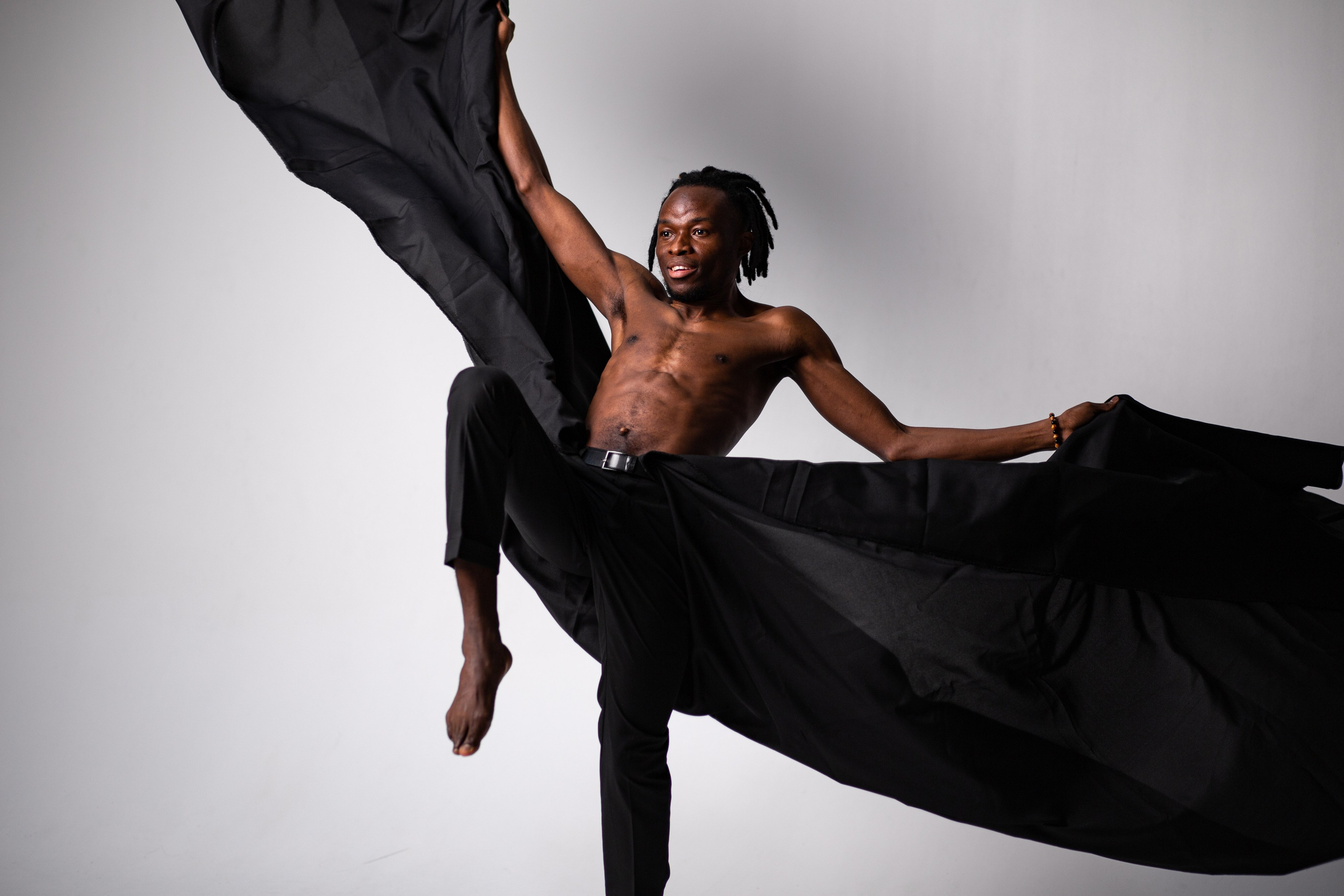 Мужчина в подтяжках и перчатках курит сигару сидя в кресле