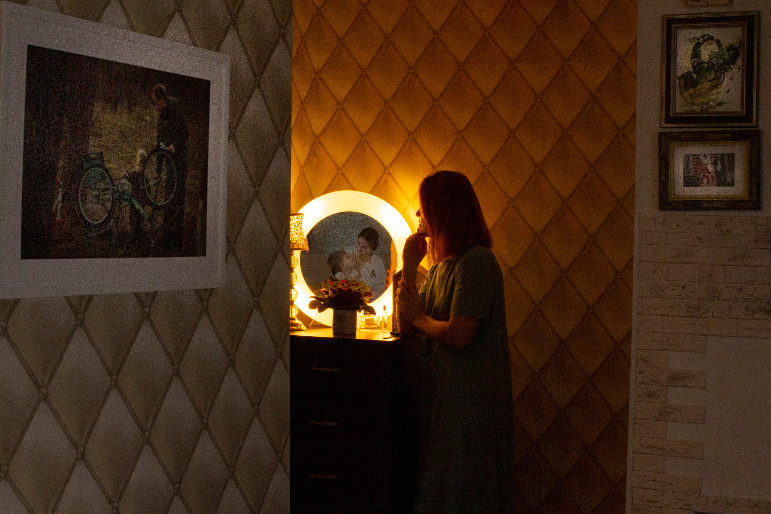 мама смотрит в зеркало где отражаются ее веселые дети сын и дочь. Вокруг много семейных фотографий.