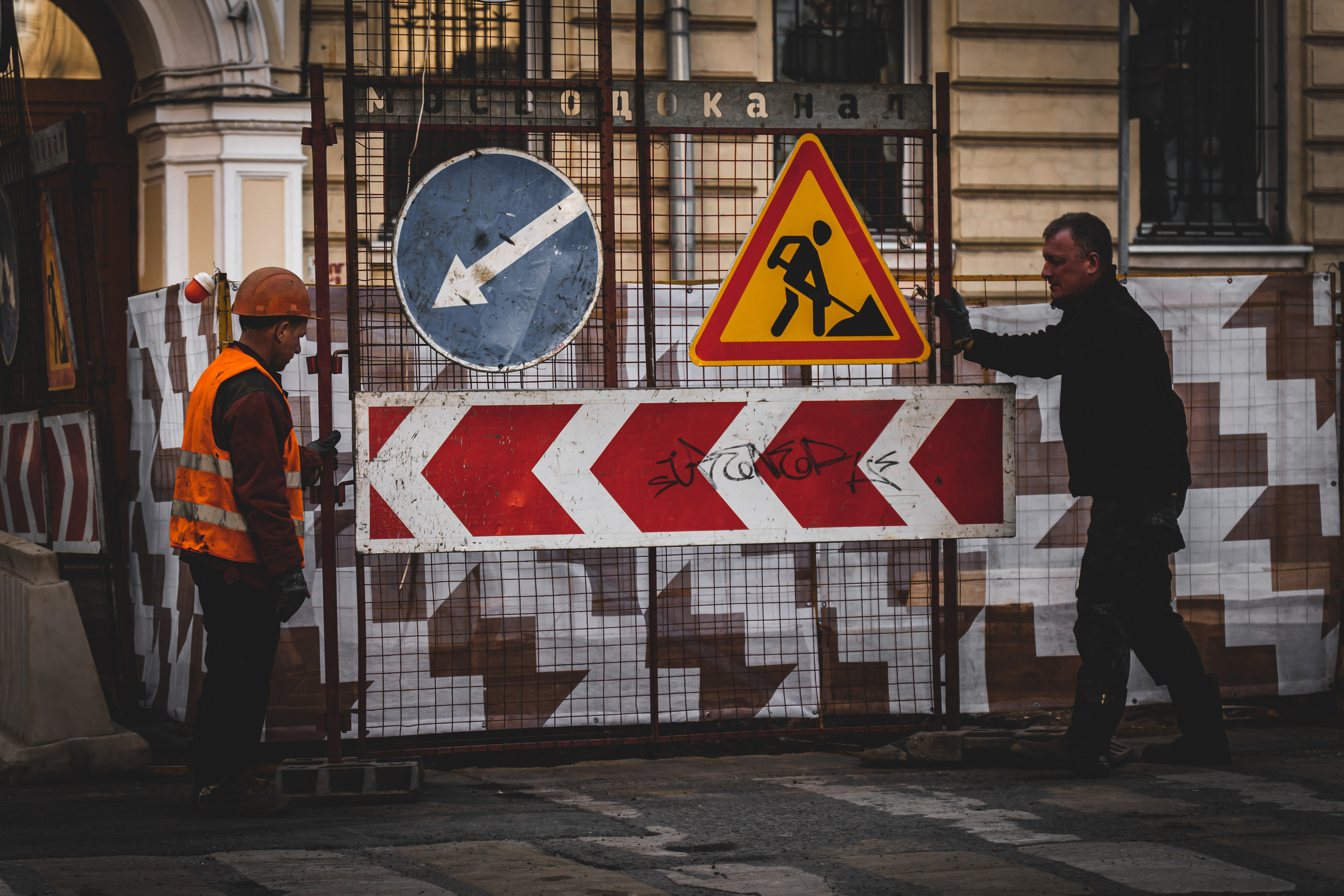 Двое рабочих передвигают дорожный знак в районе Старого Арбата в Москве