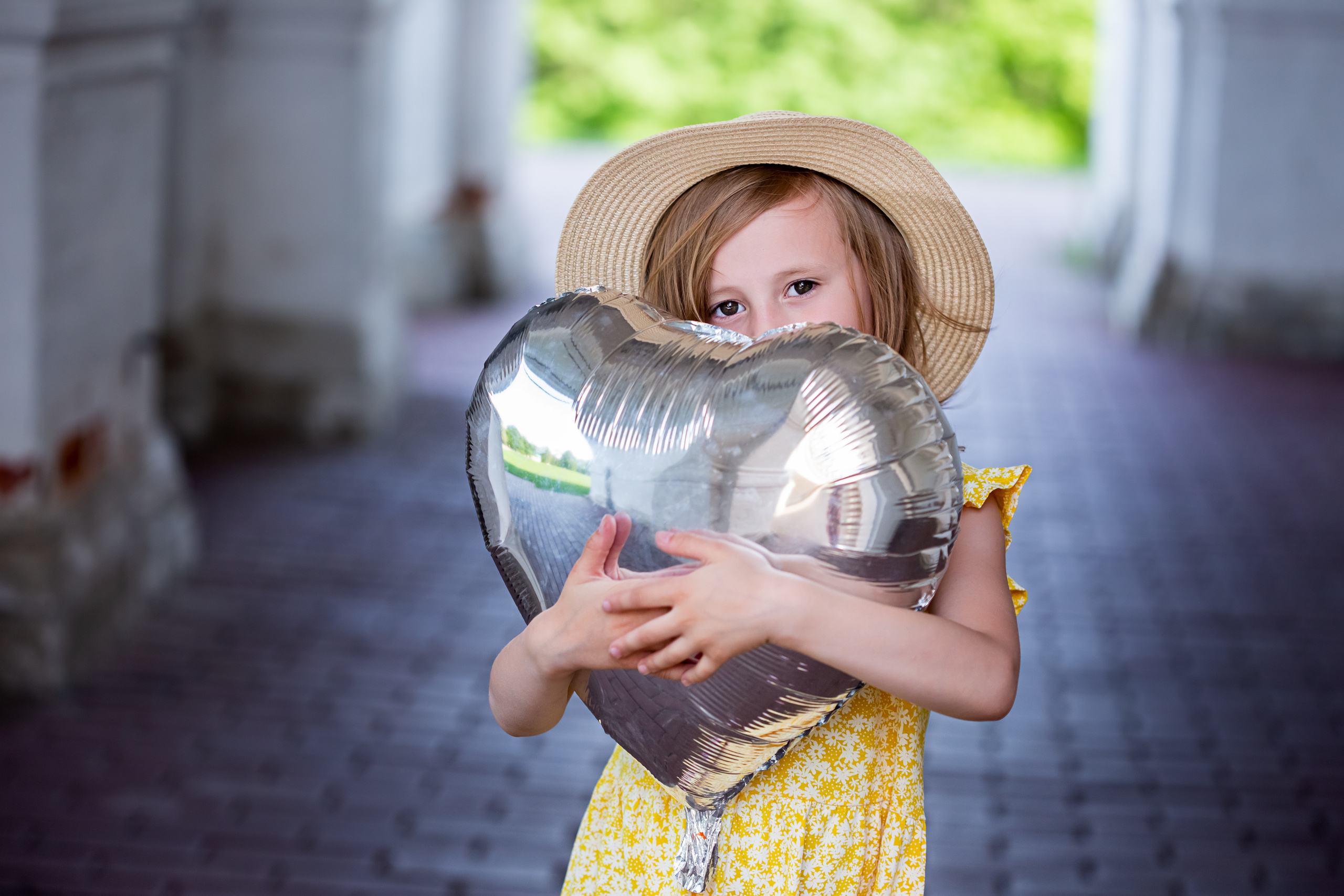 Девочка пяти лет держит в руках воздушный шарик в форме сердца