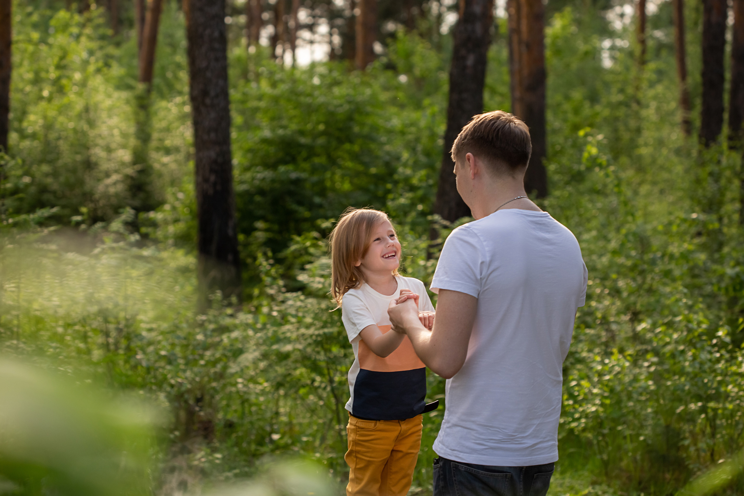 Папа с дочкой гуляют в парке и держатся за руки