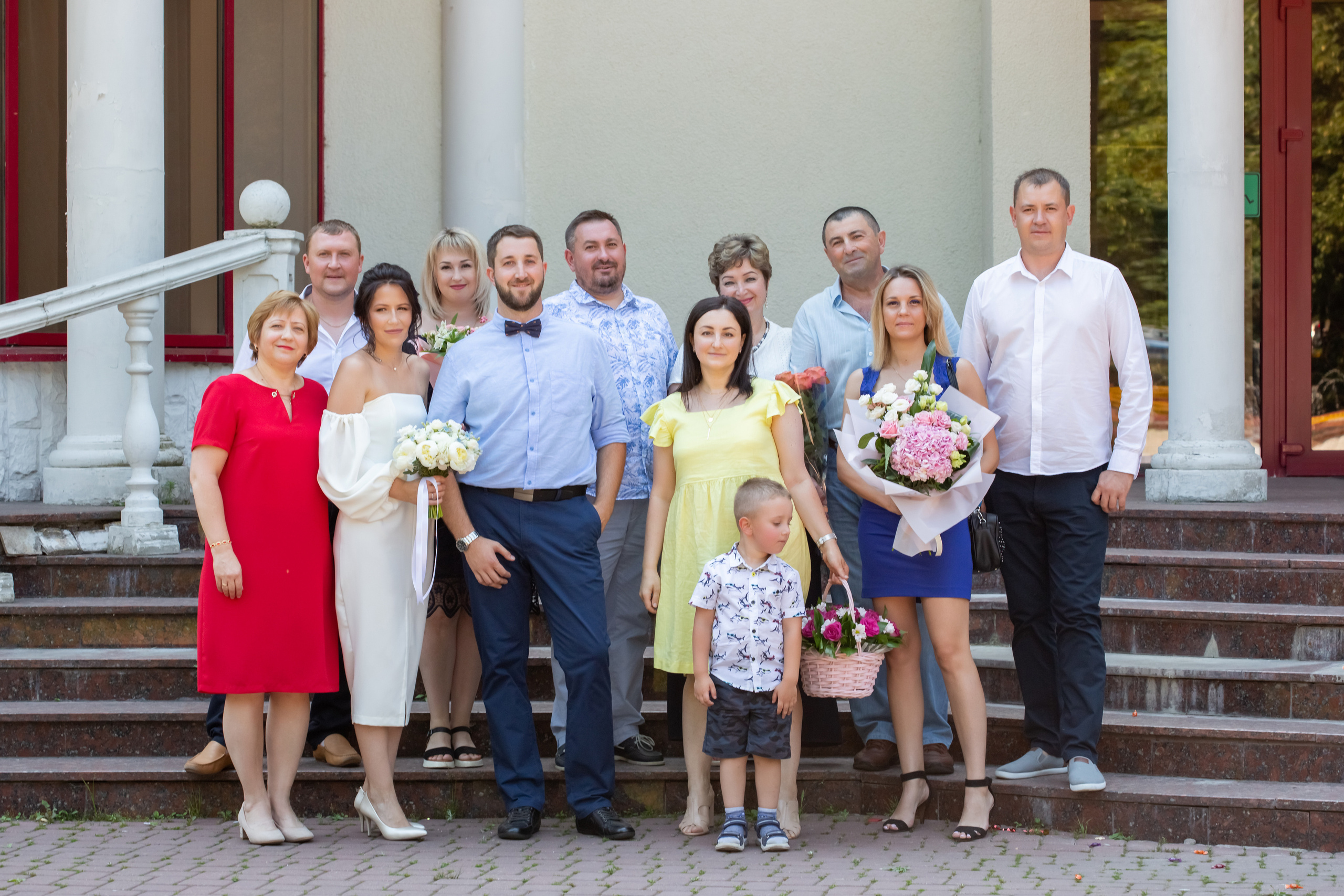 Девочка в желтом платье нюхает ветку цветущей яблони