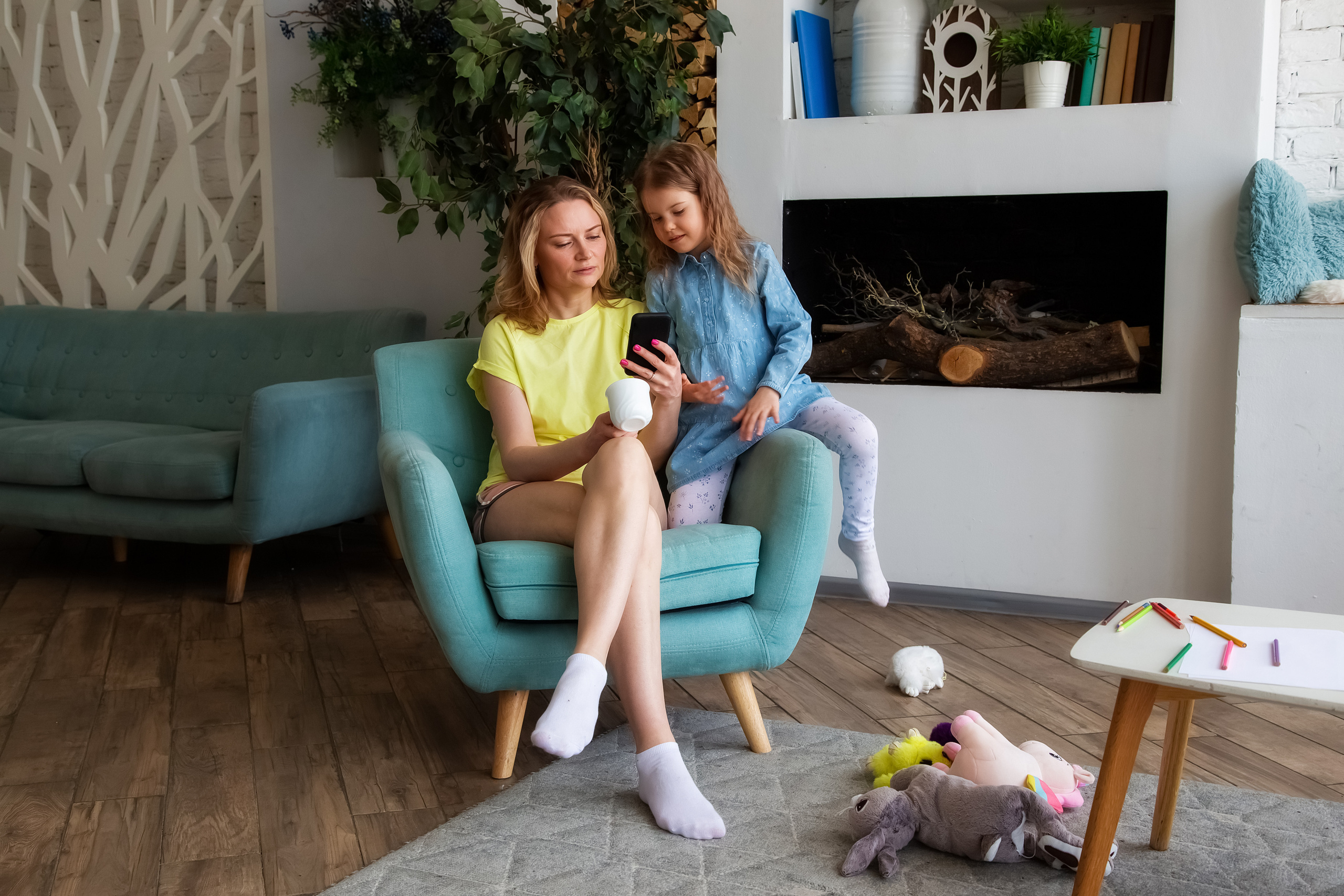 Мама с дочкой сидя в кресле делают онлайн покупки