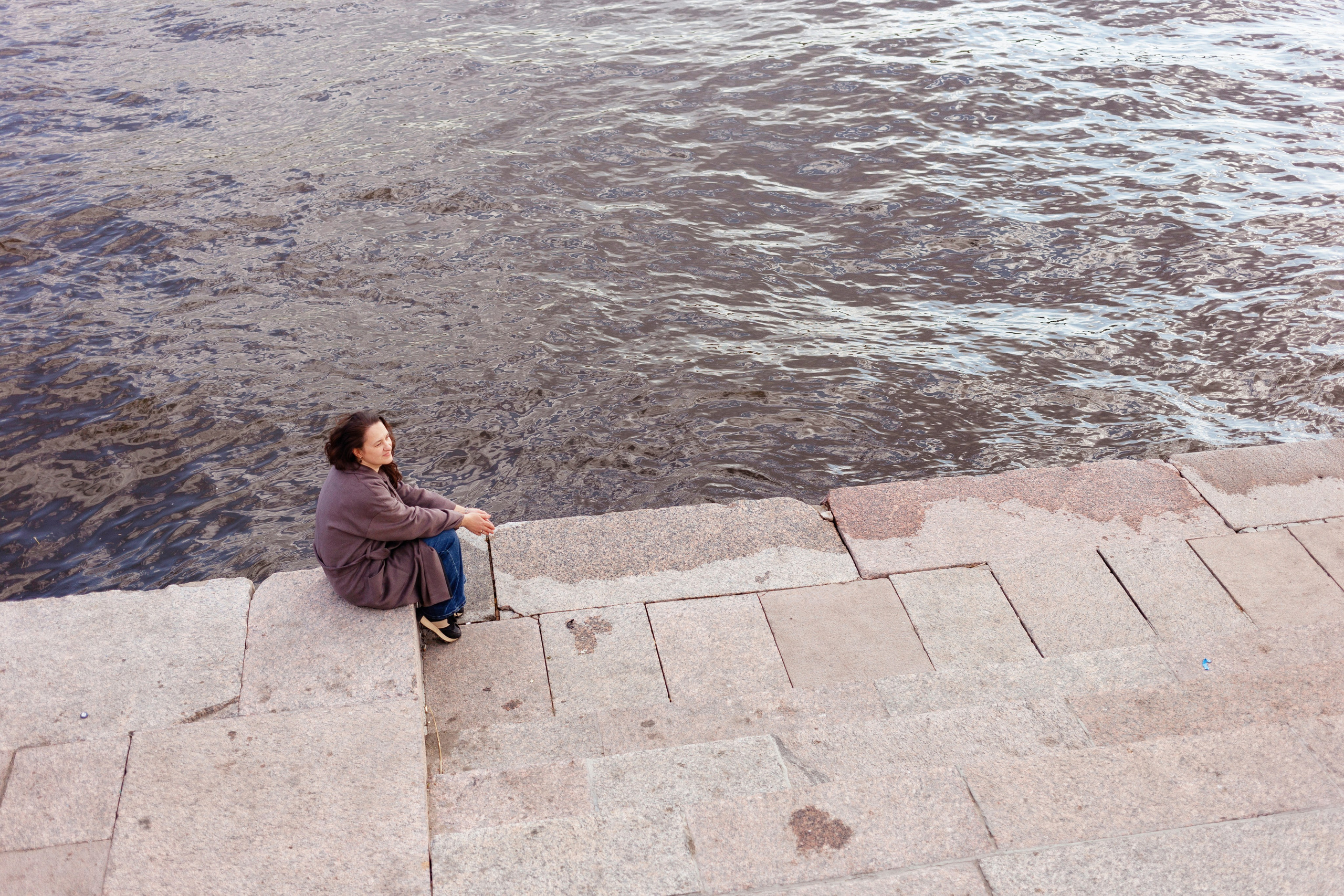 Прогулочная фотосессия в Петербурге: женщина сидит у воды на Арсенальной набережной, женский портрет, идеи для фотосессии