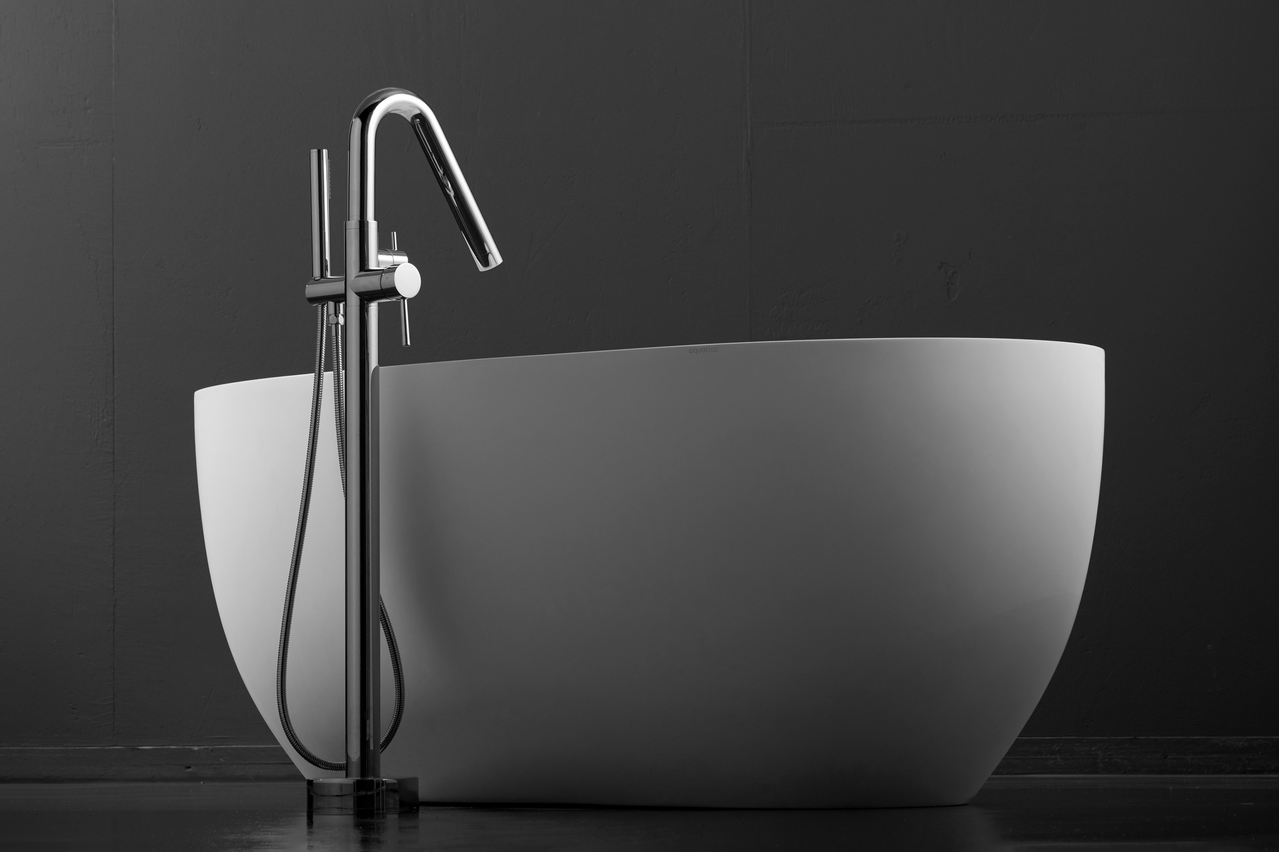 Предметная фотография современной белой раковины со смесителем на тёмном фоне