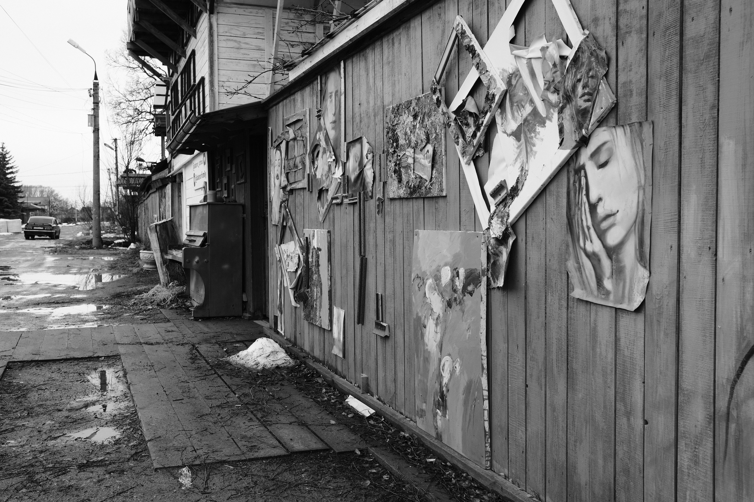 Старые портреты и картины прикрепленные к деревянной стене дома, уличное искусство, провинциальная атмосфера Переславля