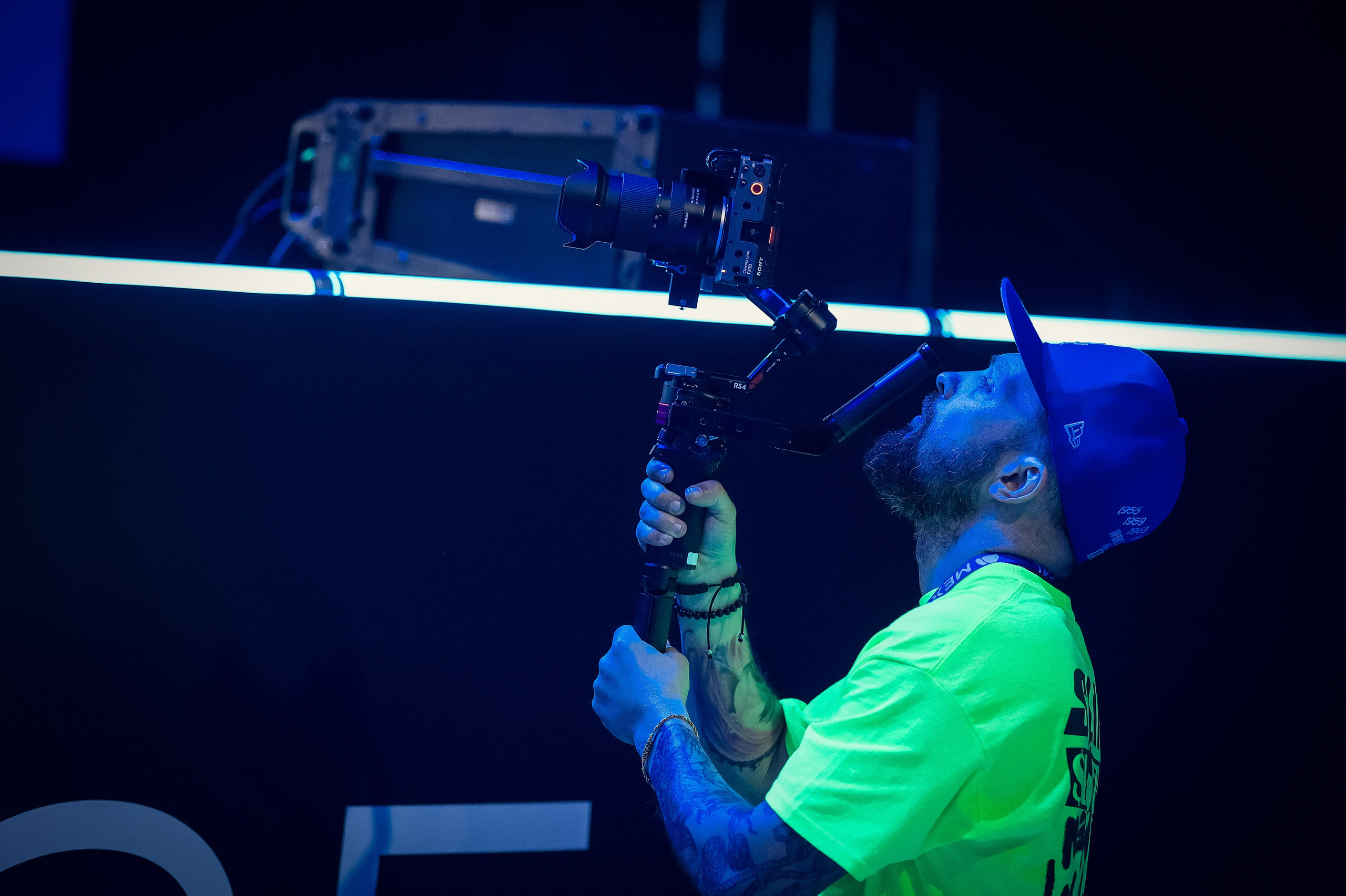 Крупный план видеооператора: один из операторов держит камеру, снимает процесс со сцены, виден локоть и часть оборудования.