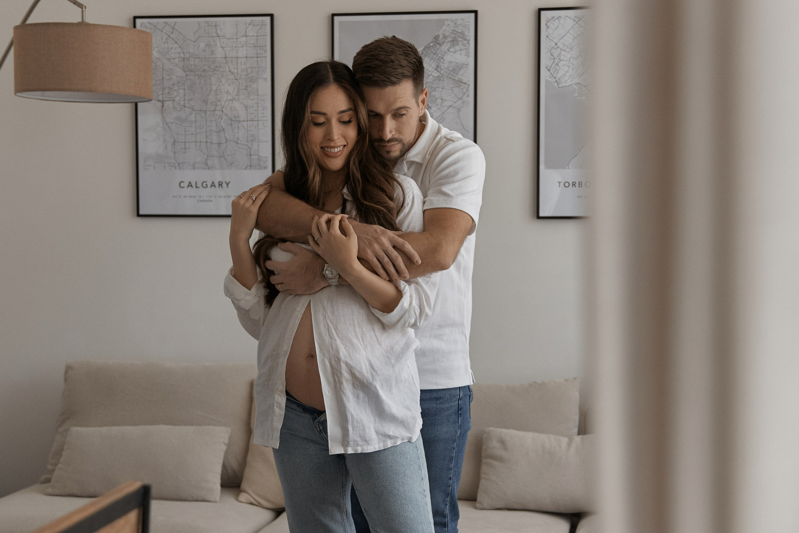 A couple shares a loving embrace in their living room, with a dog resting on the floor