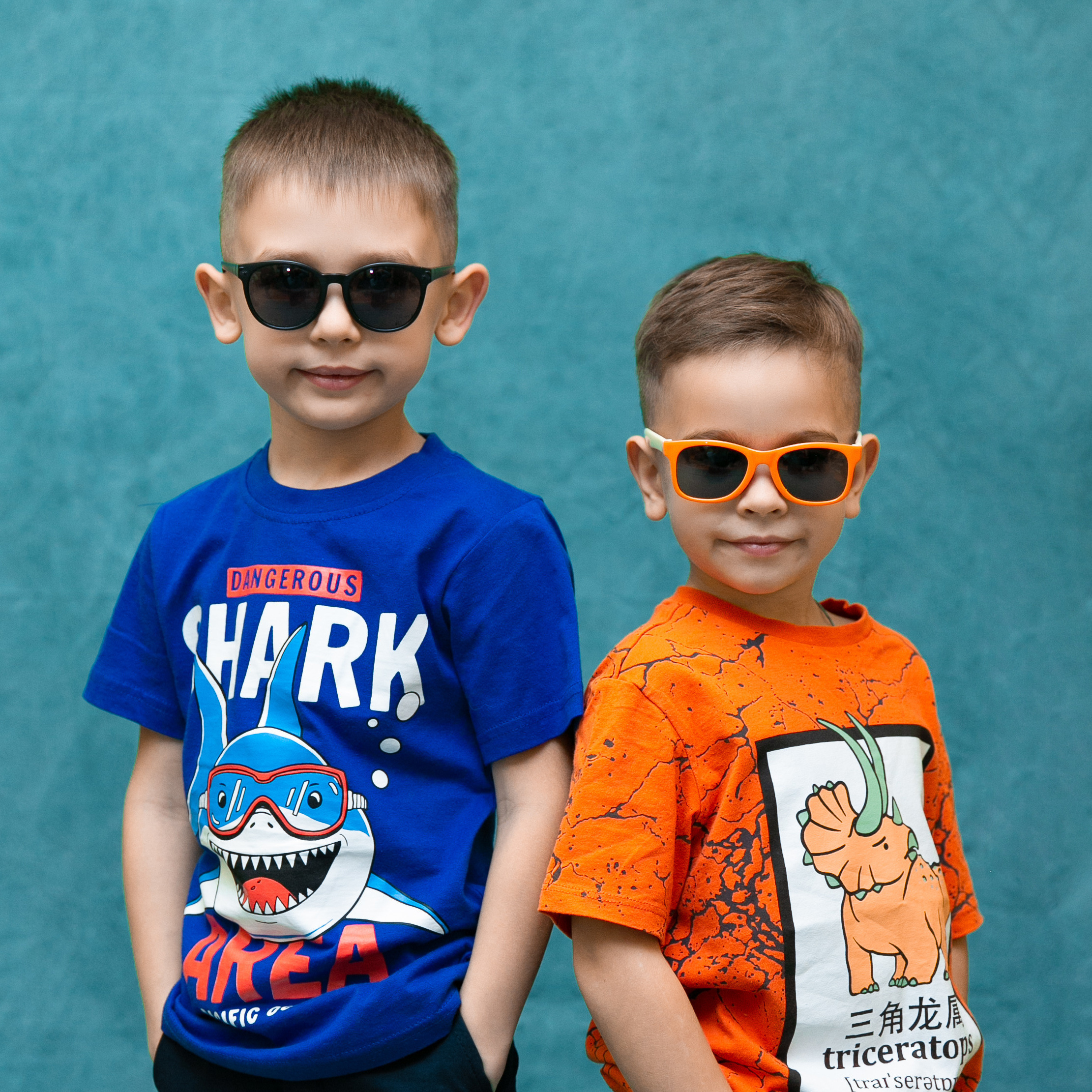 Два мальчика из детского сада в синей и оранжевой футболке стоят рядом, на них солнечные очки. Фото школьного фотографа студии Вышка.