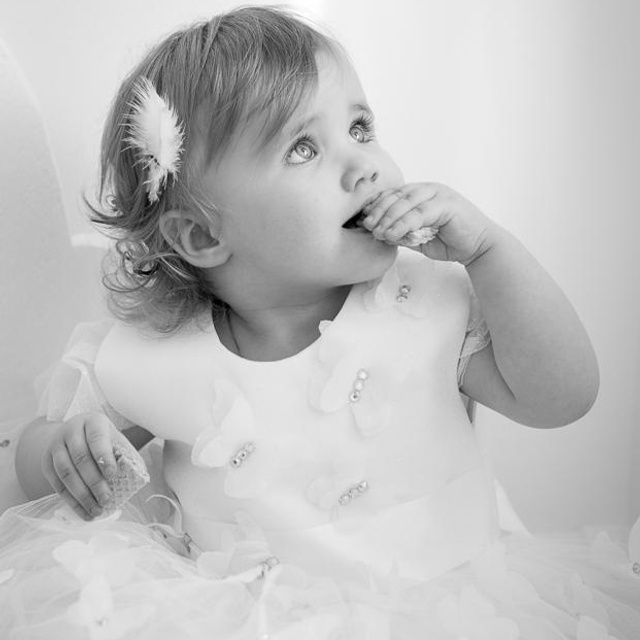 Фотосессия маленькой принцессы в пышной юбке и перьях ест печенье