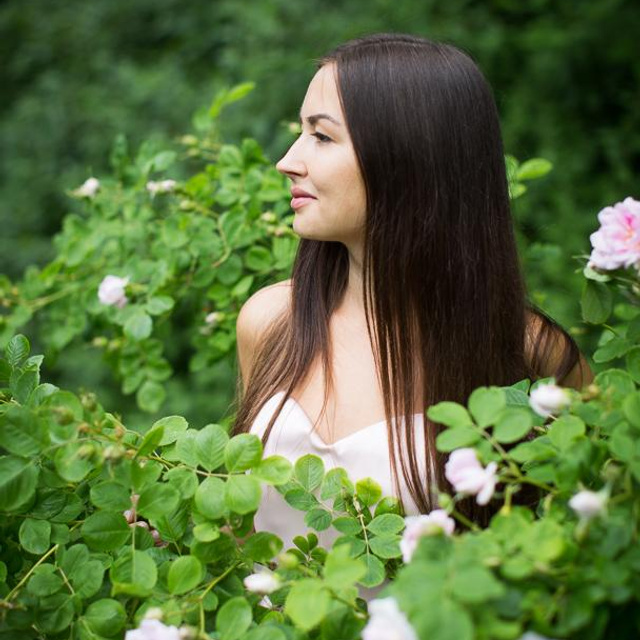 Фотопортрет красивой девушки брюнетки в цветущих розах в парке Петербурга  