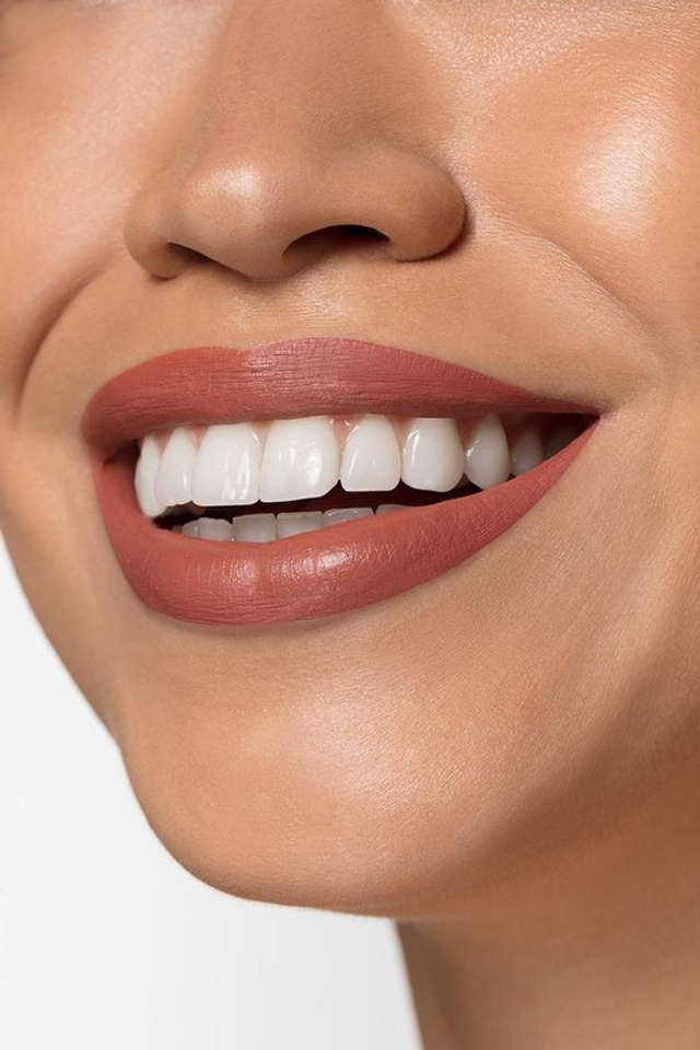 Предметная съемка зубной пасты в композиции с моделью на светлом фоне.